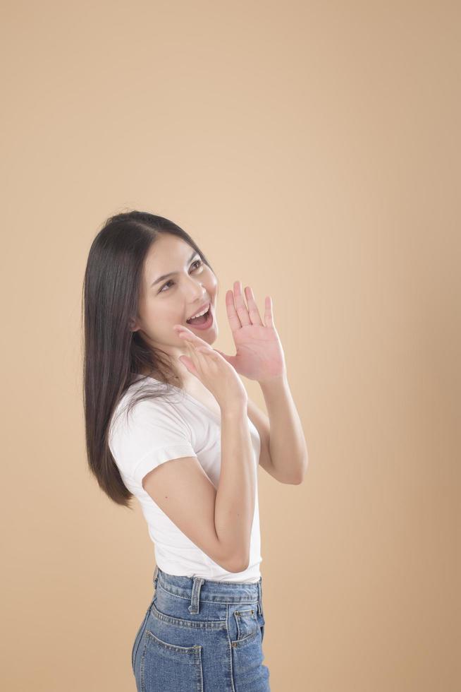 A Portrait of Asian woman with white T-shirt over Light brown background studio photo