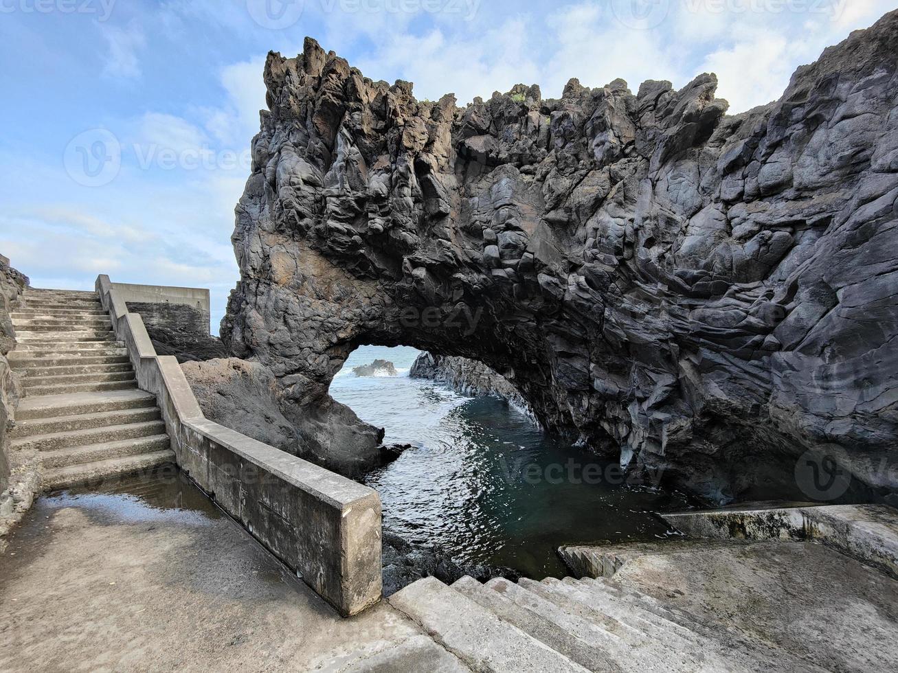 hermosas formaciones rocosas naturales con curvas junto al océano. piscinas naturales y escaleras de hormigón junto a ella. isla de madeira, portugal. destino de vacaciones tropical y sorprendente. foto