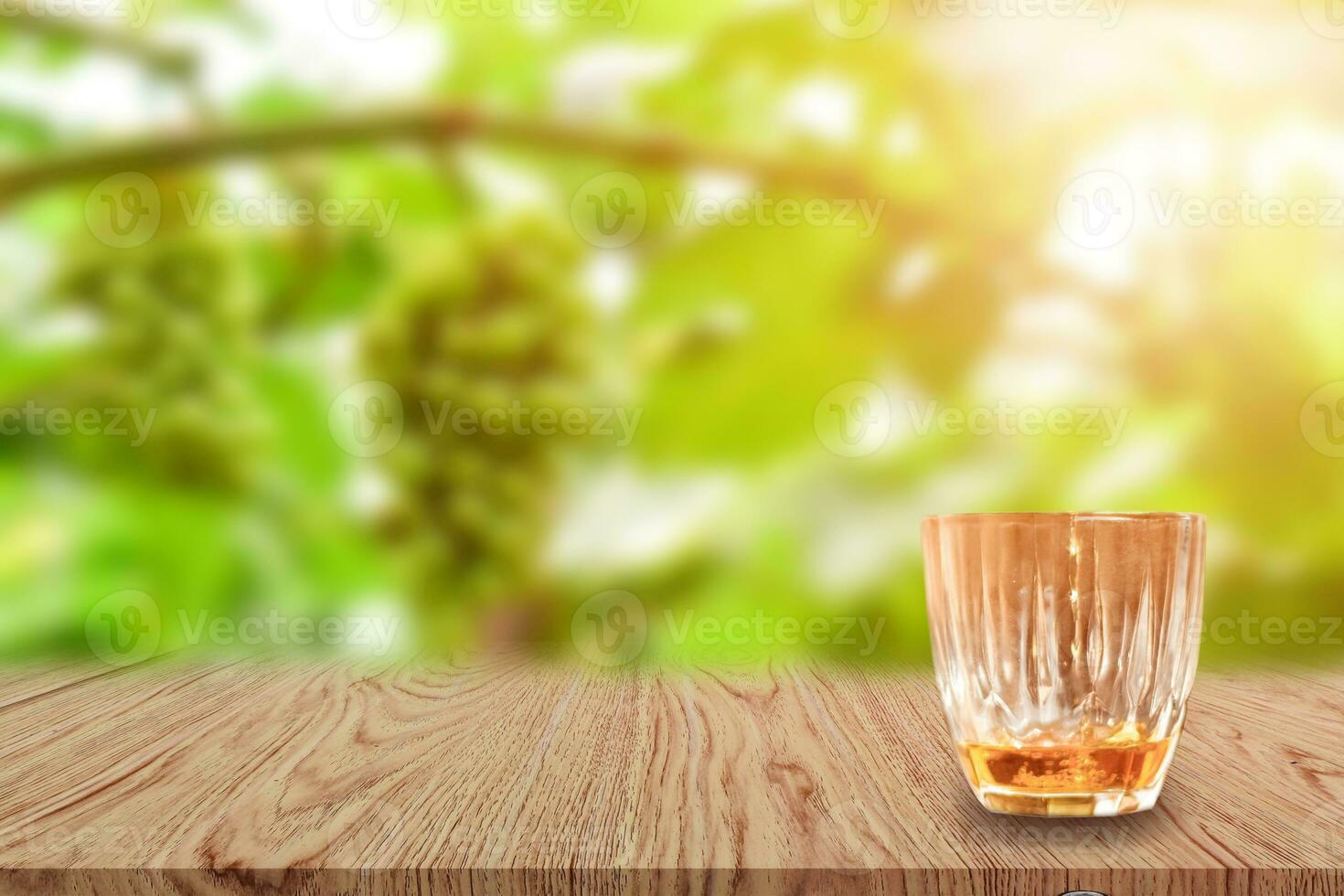 un vaso de whisky sobre una mesa de madera y un fondo natural claro y borroso. foto