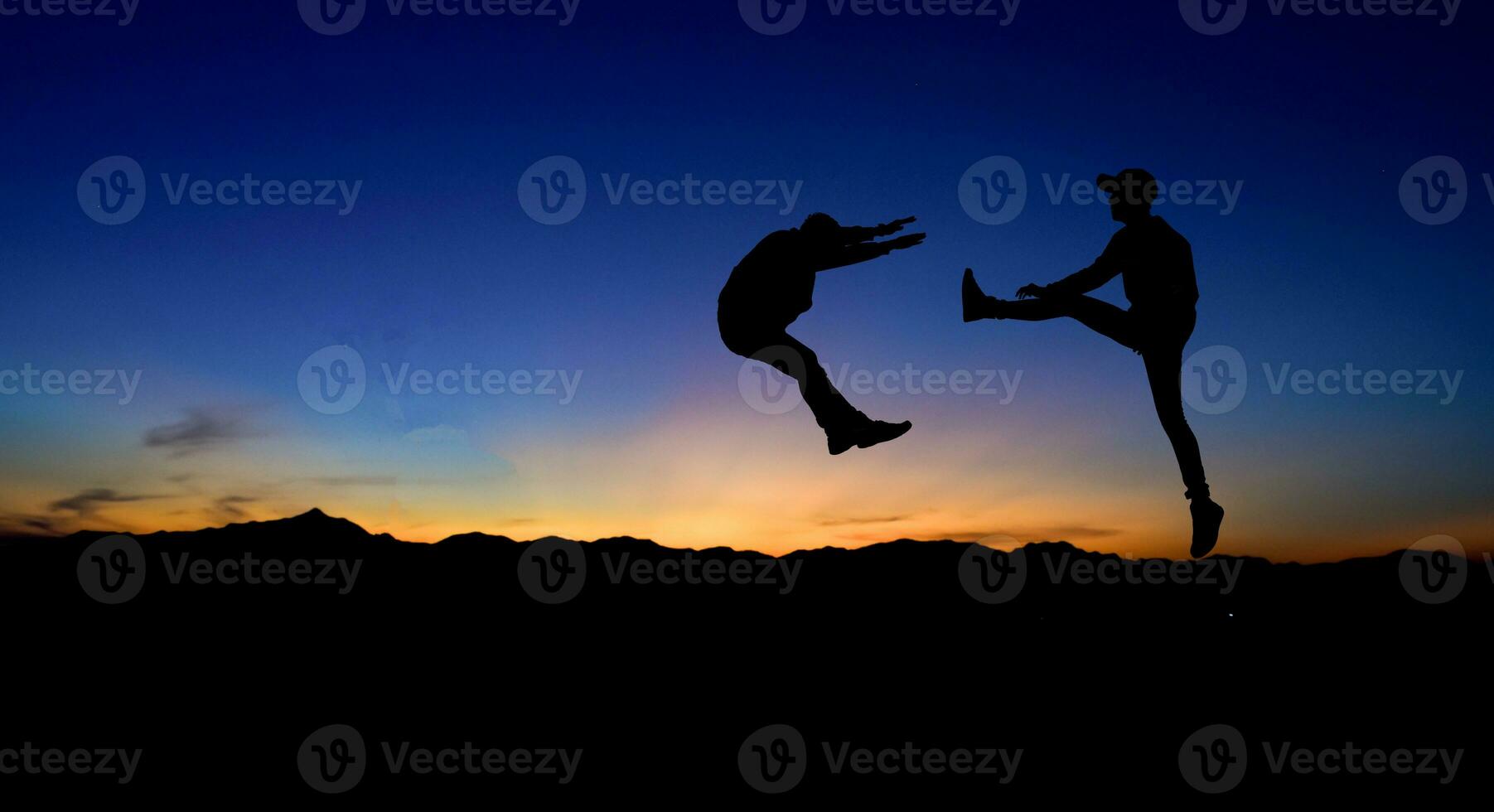 Silhouettes of two male fighters on sunset background. photo