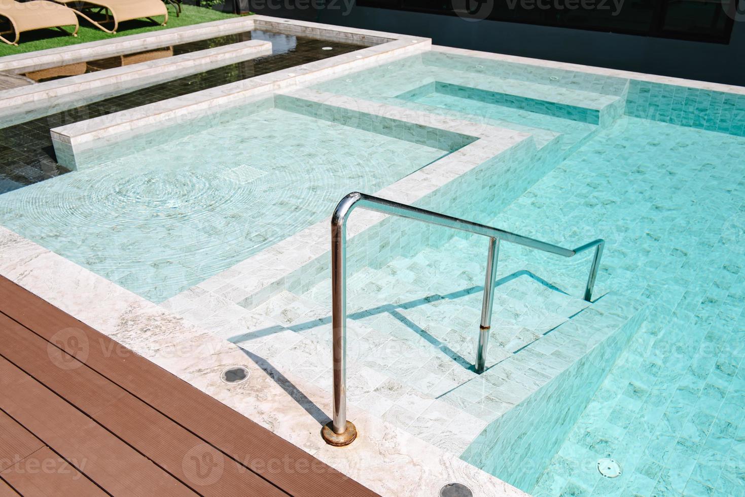 escalera de piscina y tumbona junto a la piscina, lujosa piscina al aire libre y decoración moderna del hotel resort. piscina de relajación en vacaciones de verano y estilos de vida de vacaciones de ocio. foto