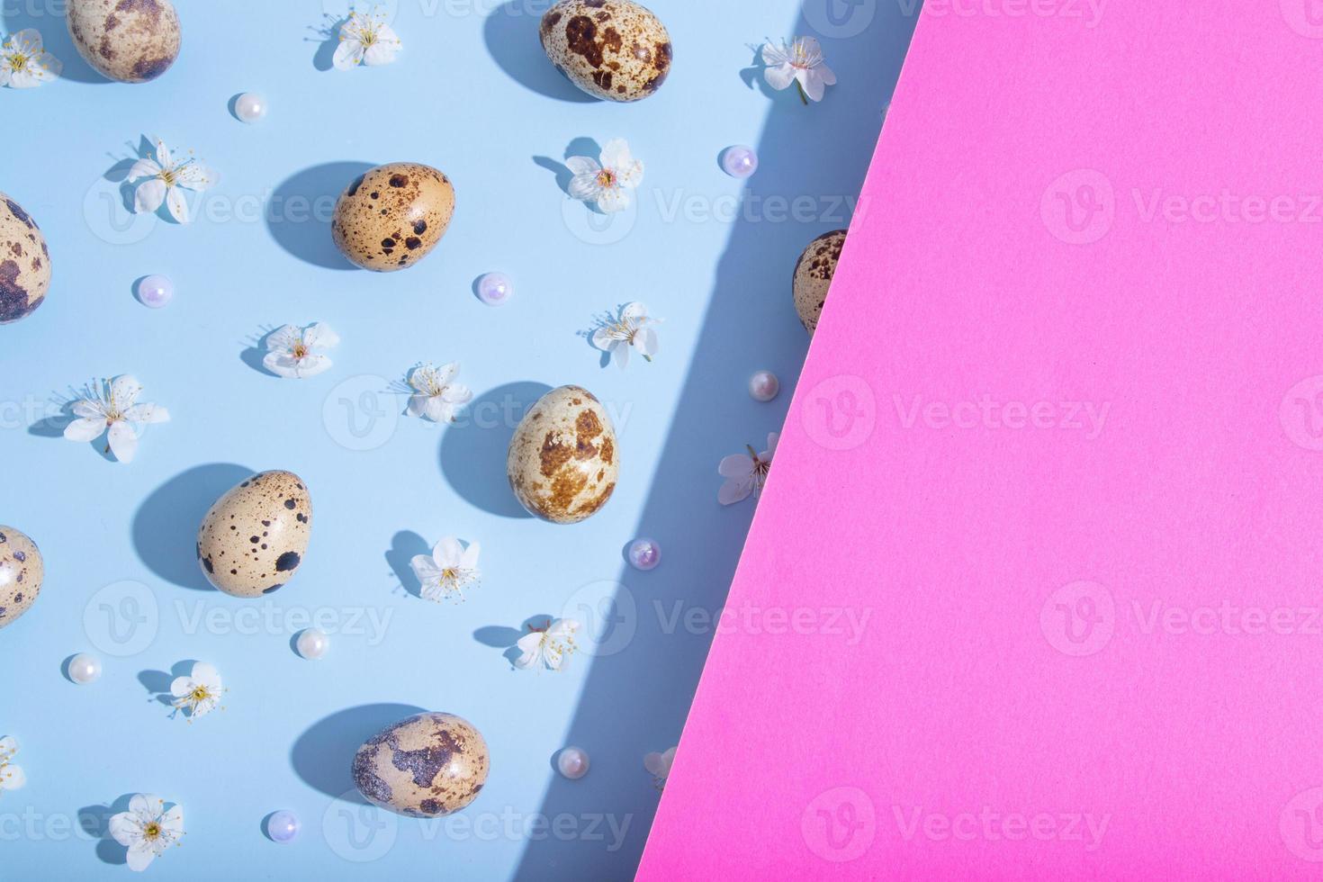 Minimalistic Flat lay, top view composition with easter eggs and cherry flowers pattern on blue-pink background. Trendy minimal style. photo