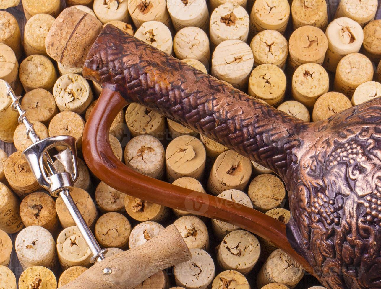 Clay bottle, metal corkscrew and cork on a wooden table photo