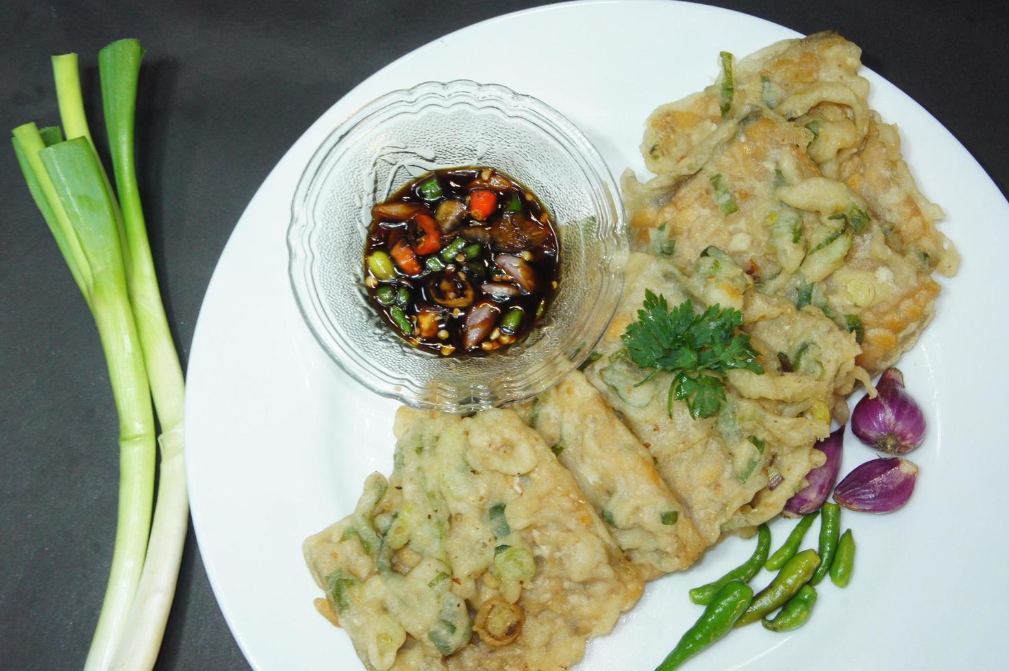 A traditional Javanese, Indonesian food made of tempeh coated with flour and half-fried green onions is called Tempe Mendoan photo