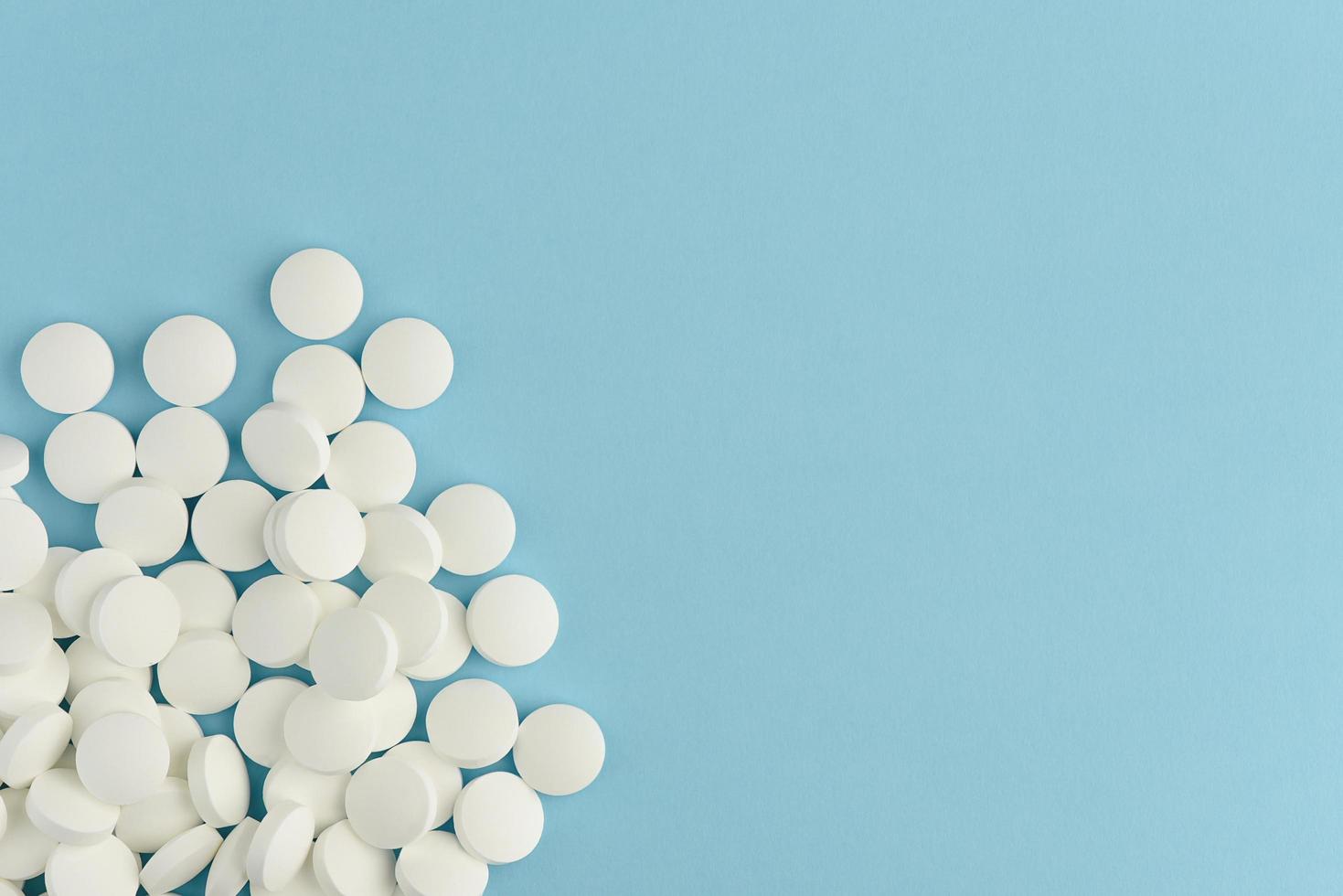 White round pills scattered on blue background. Medicine flat lay. photo