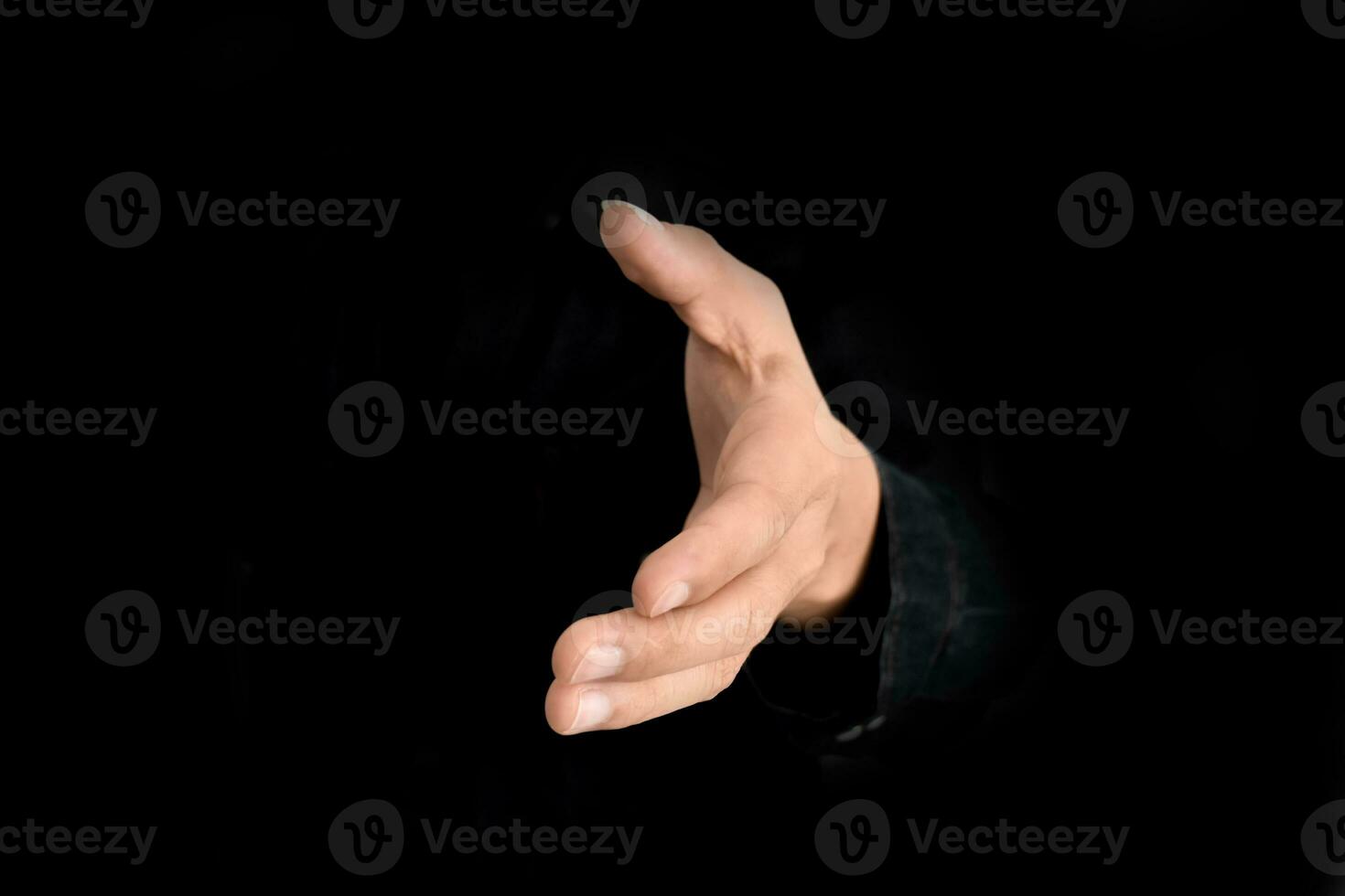 Businessman offer hand for handshake and cooperation over black background. Business deal proposal concept. photo