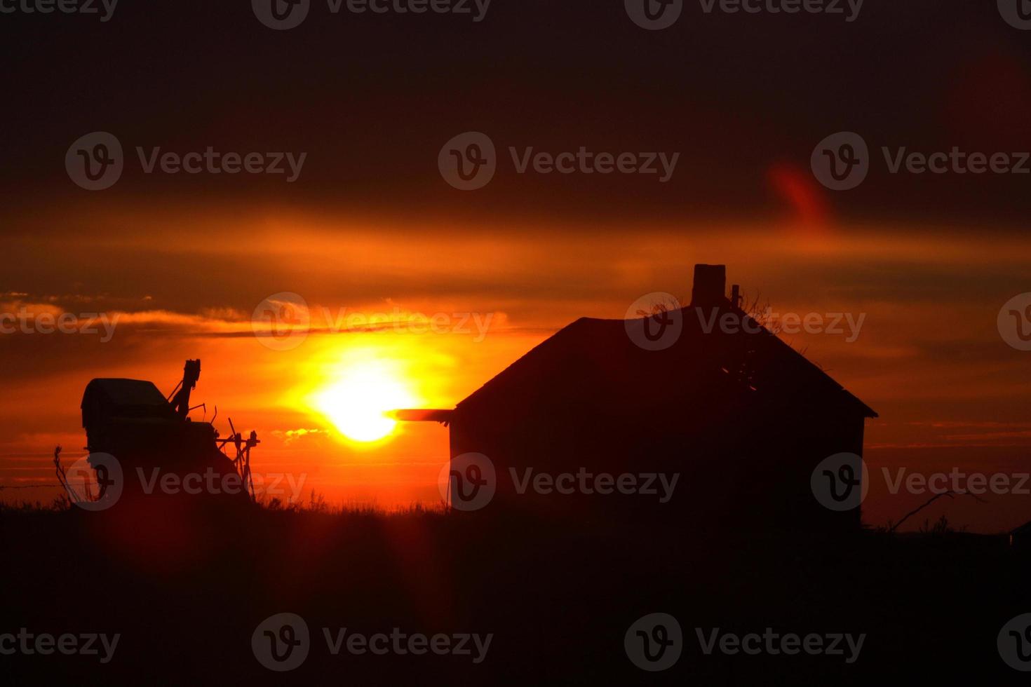 Sun setting behind old Saskatchewan farm buildings photo