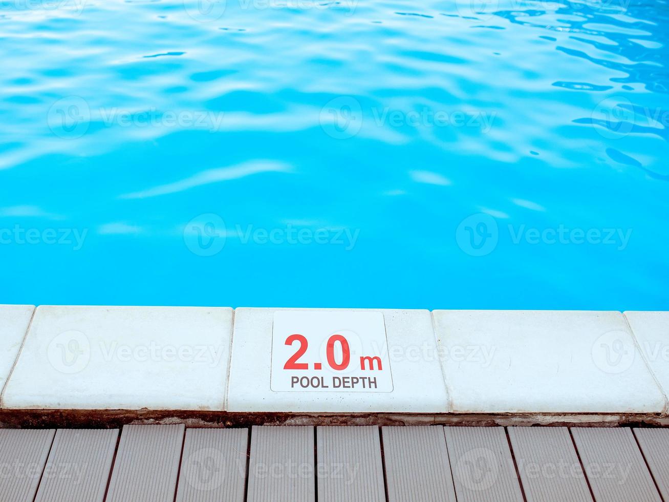 The edge of the swimming pool with the table with information of the depth in English language. Sport, safety, recreation and relax concept. photo