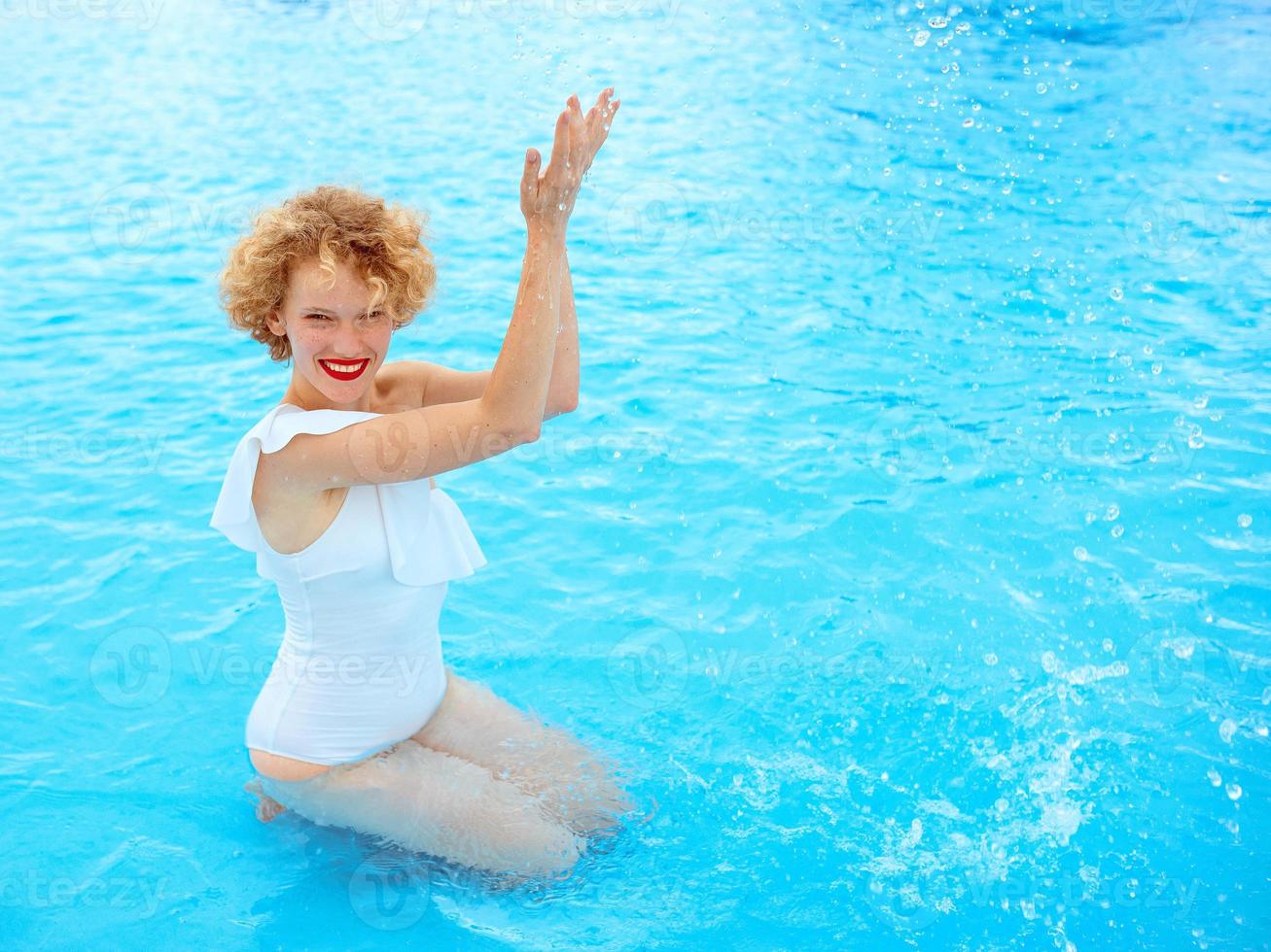 smiling redhead woman portrait enjoying life in white swimming suit in the swimming pool photo