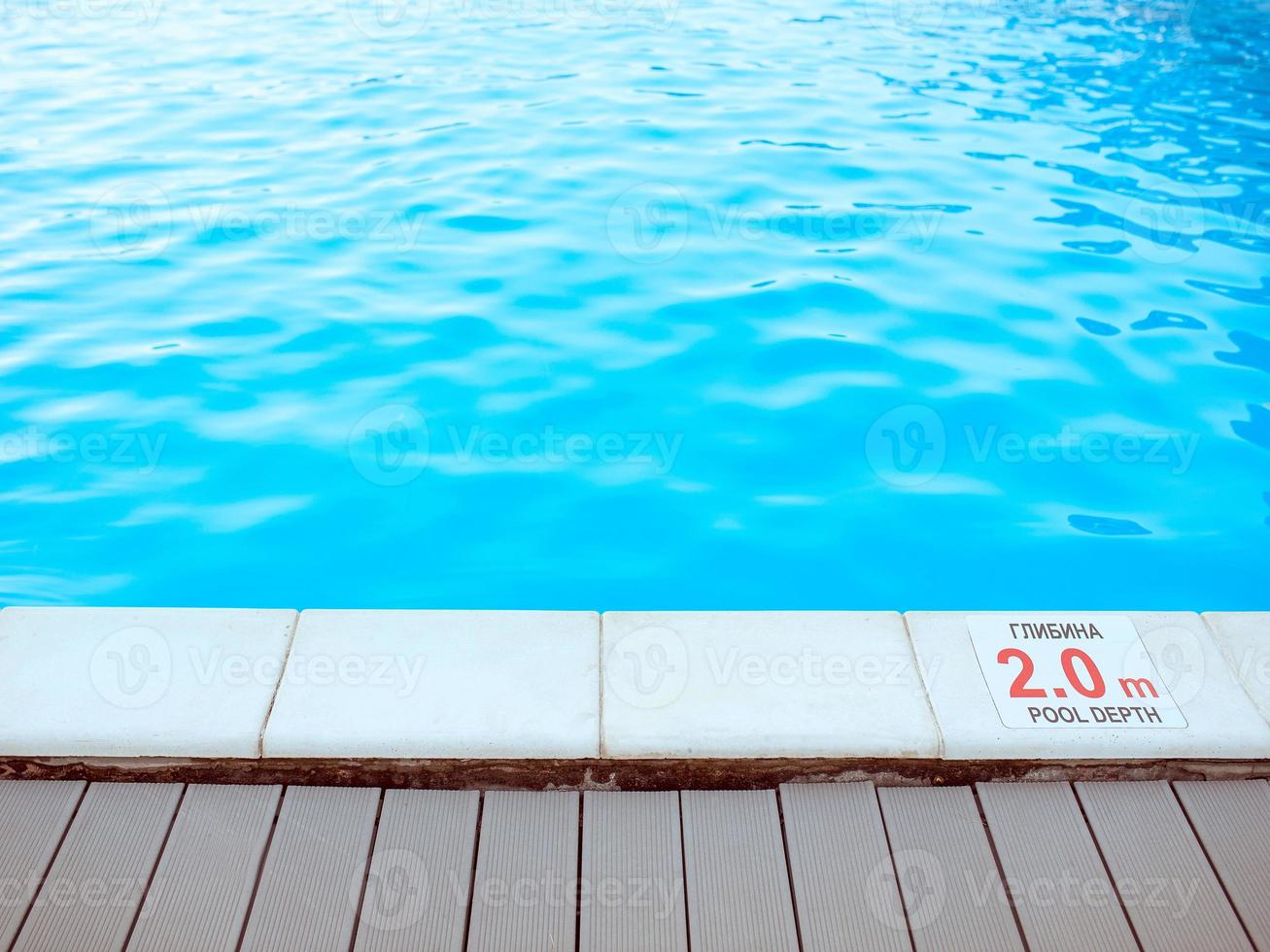 The edge of the swimming pool with the table with information of the depth in English and Ukrainian language. Sport, safety, recreation and relax concept. photo