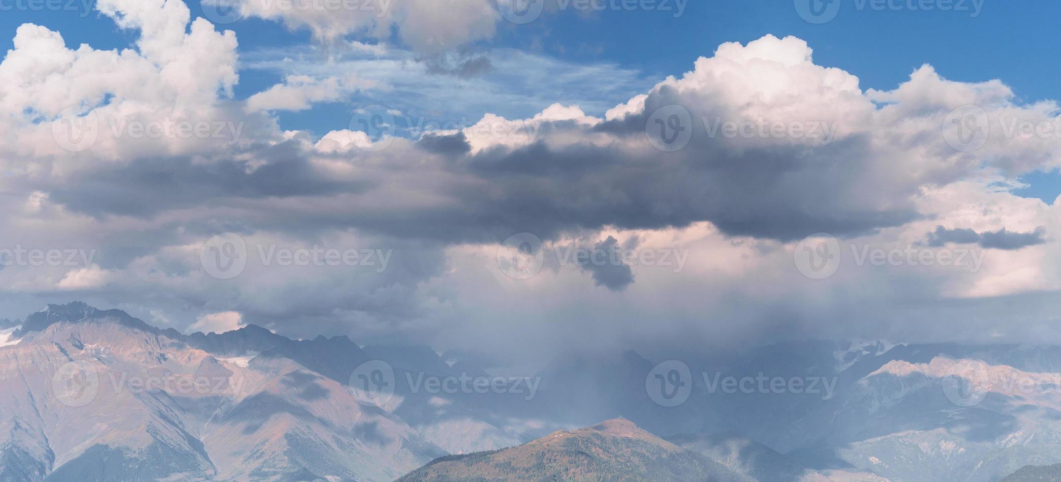 fantásticas montañas nevadas en las hermosas nubes cúmulos. dorsal caucásica principal. foto