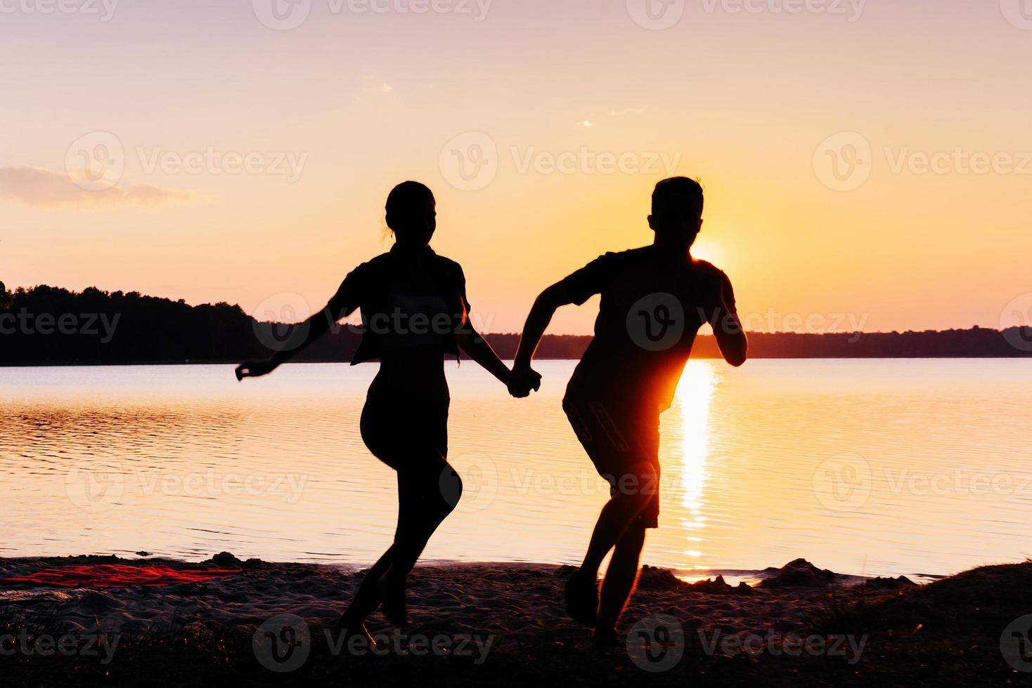 Romantic couple on the beach at colorful sunset on background photo