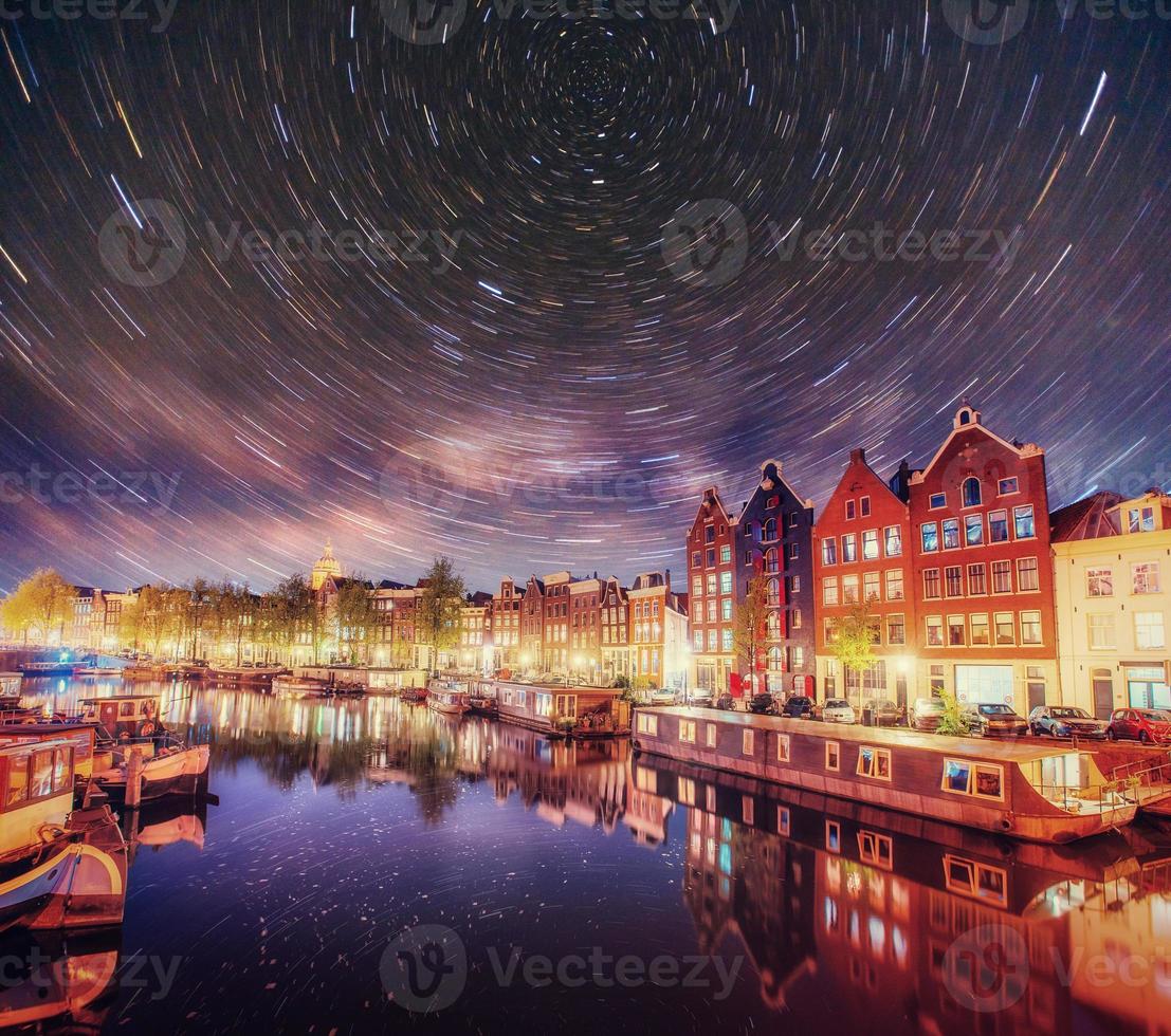 hermosa noche en amsterdam. Iluminación nocturna de edificios y barcos cerca del agua en el canal. foto