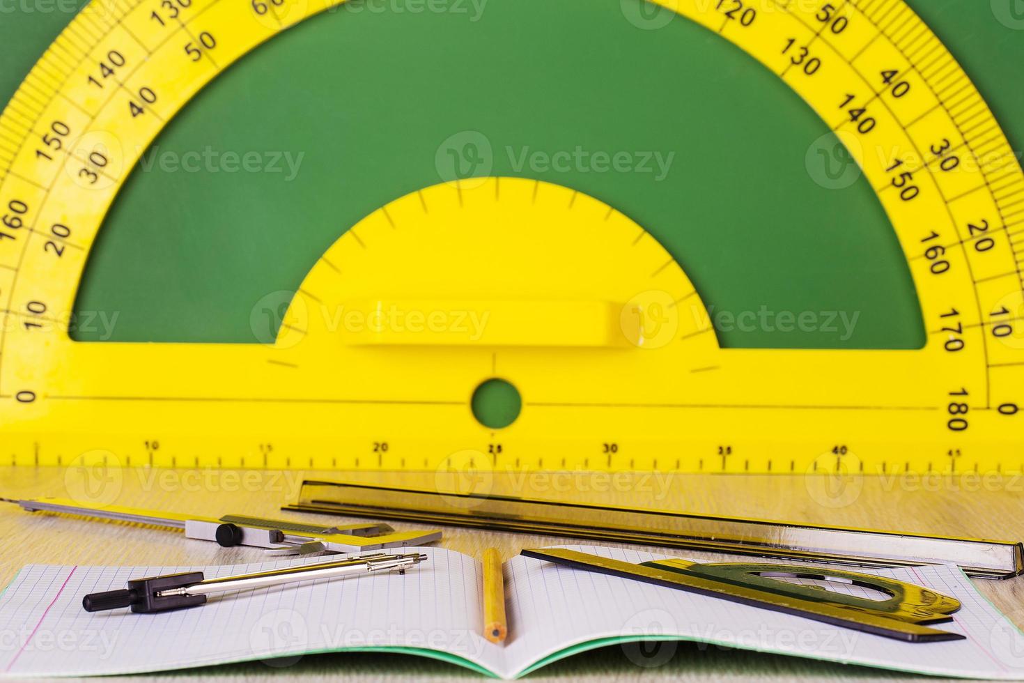 pencil, compass, notebook, ruler, caliper and green chalkboard with protractor photo