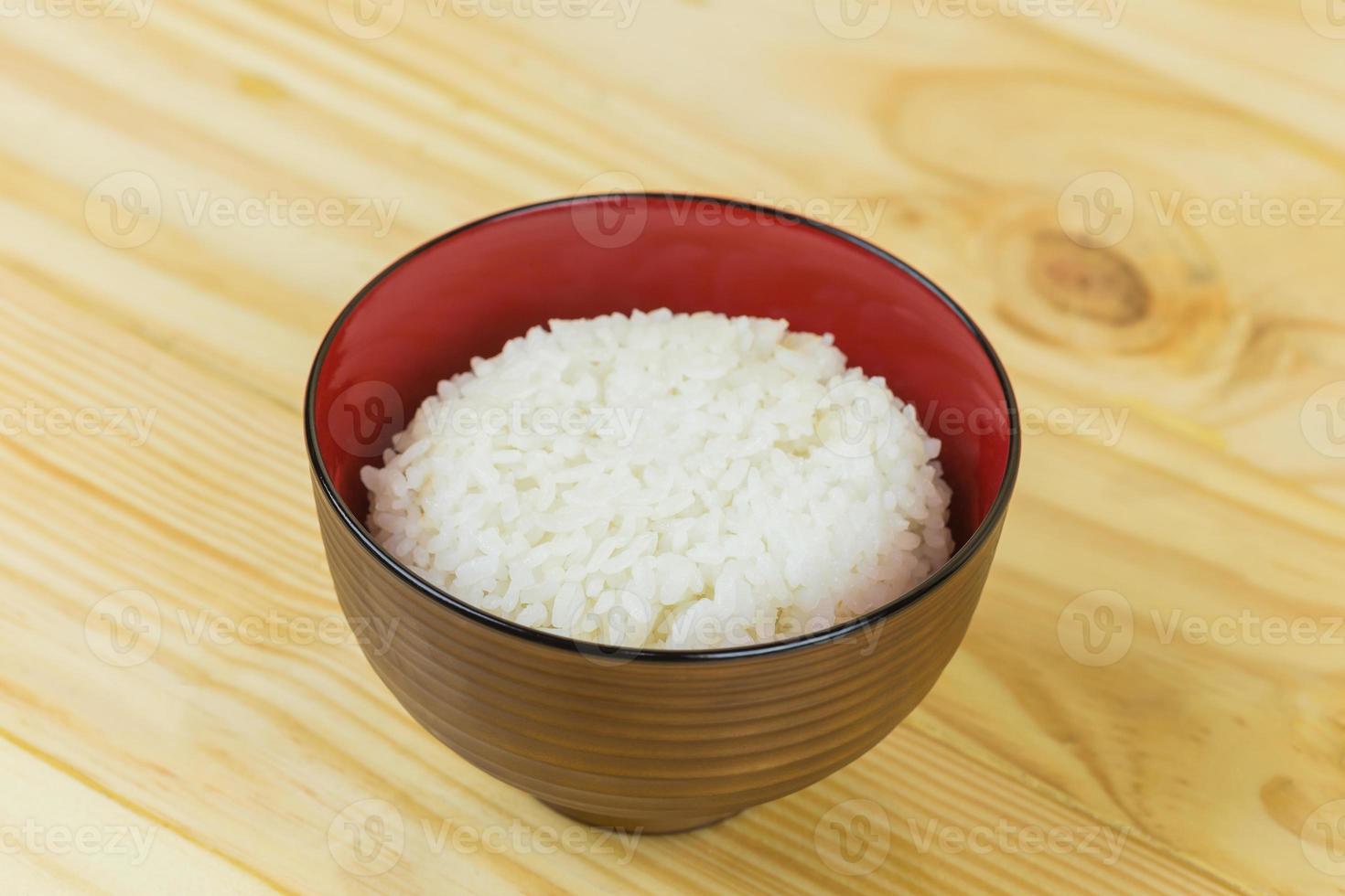 Cooked jasmine rice in white bowl on wooden table and dark background with copy space,high calories food,Top view. photo