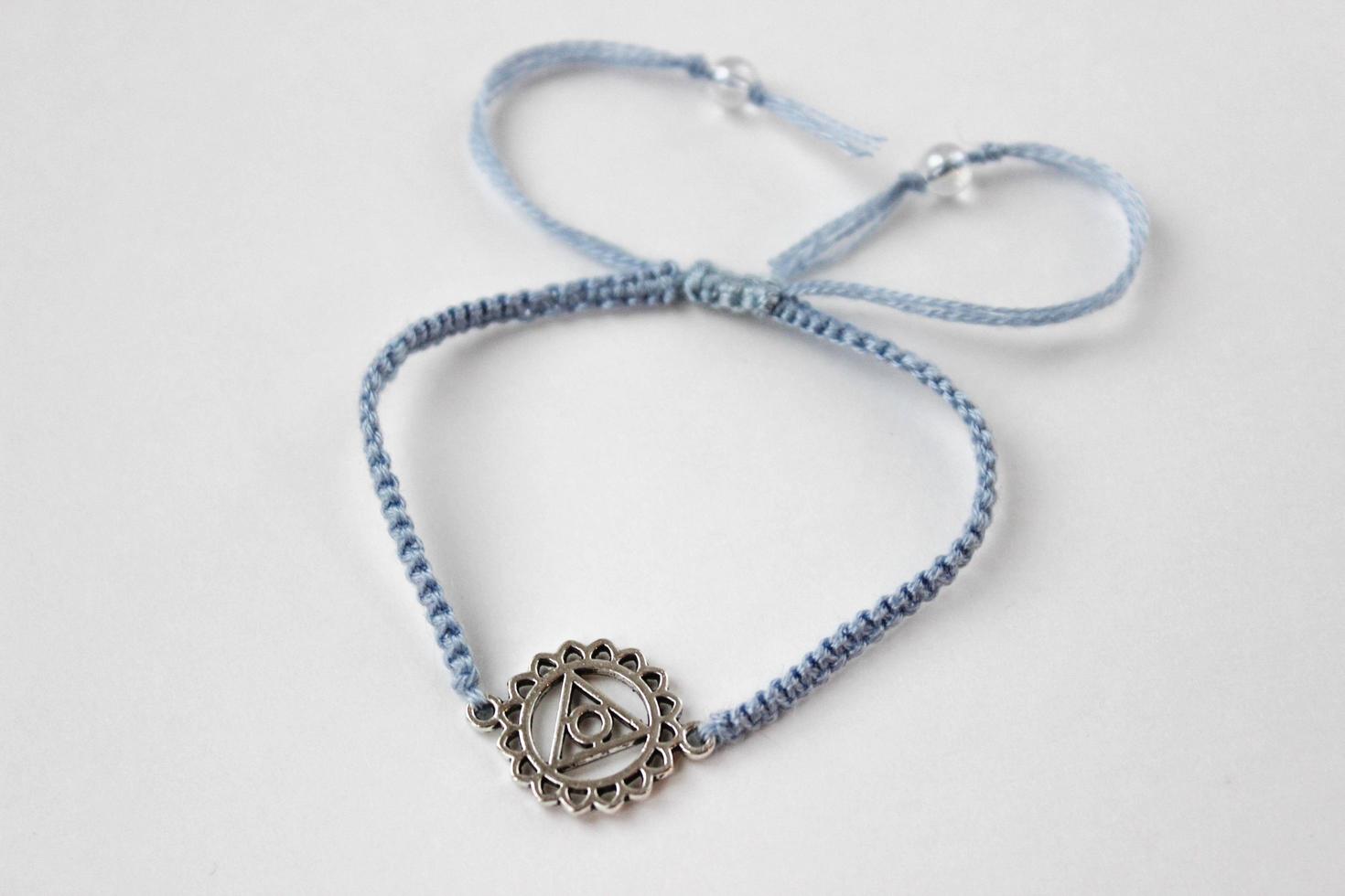 Pulsera braded azul con chakra vishuddha sobre fondo blanco. foto