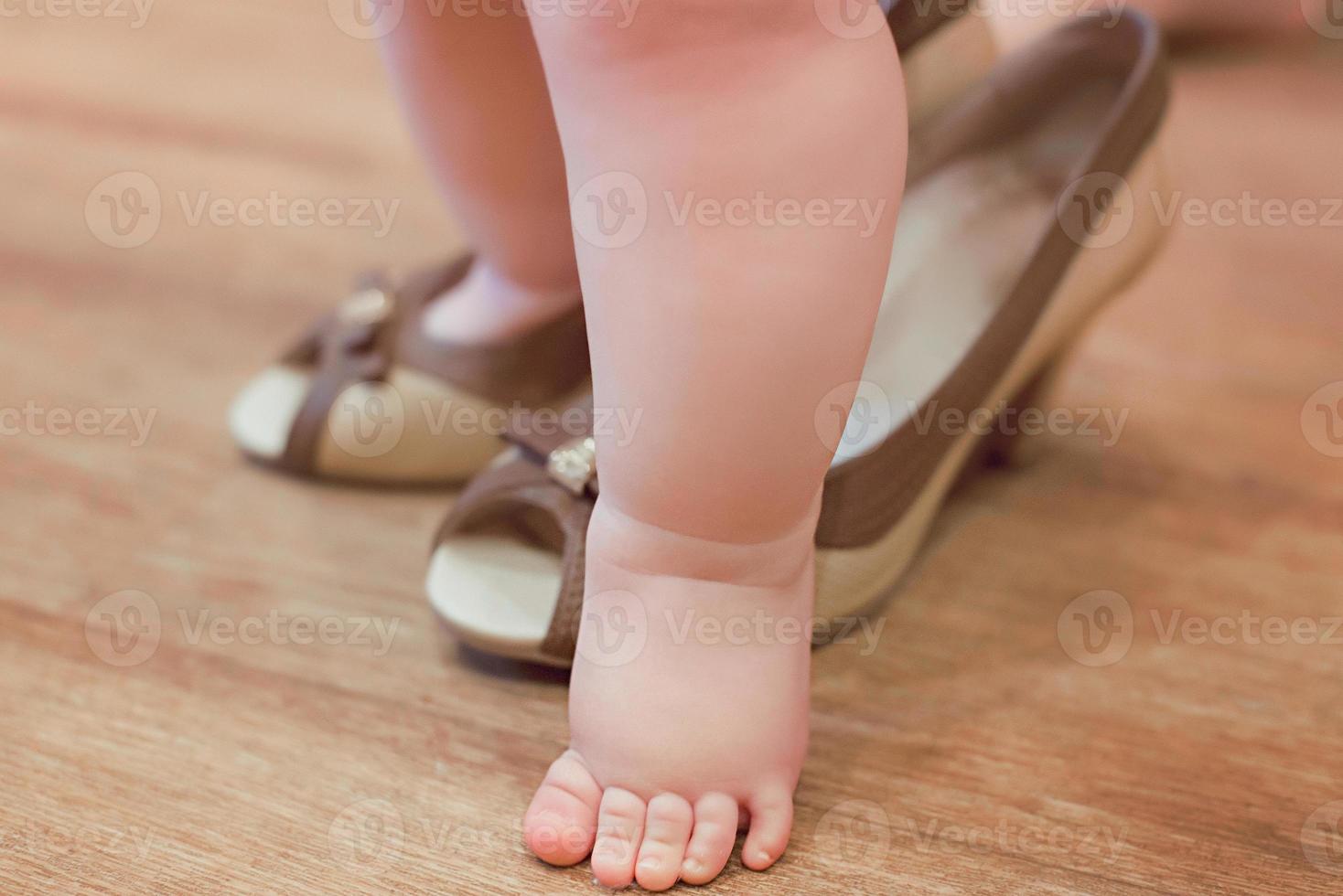 Little baby infant playing adult in mother's heel shoes photo
