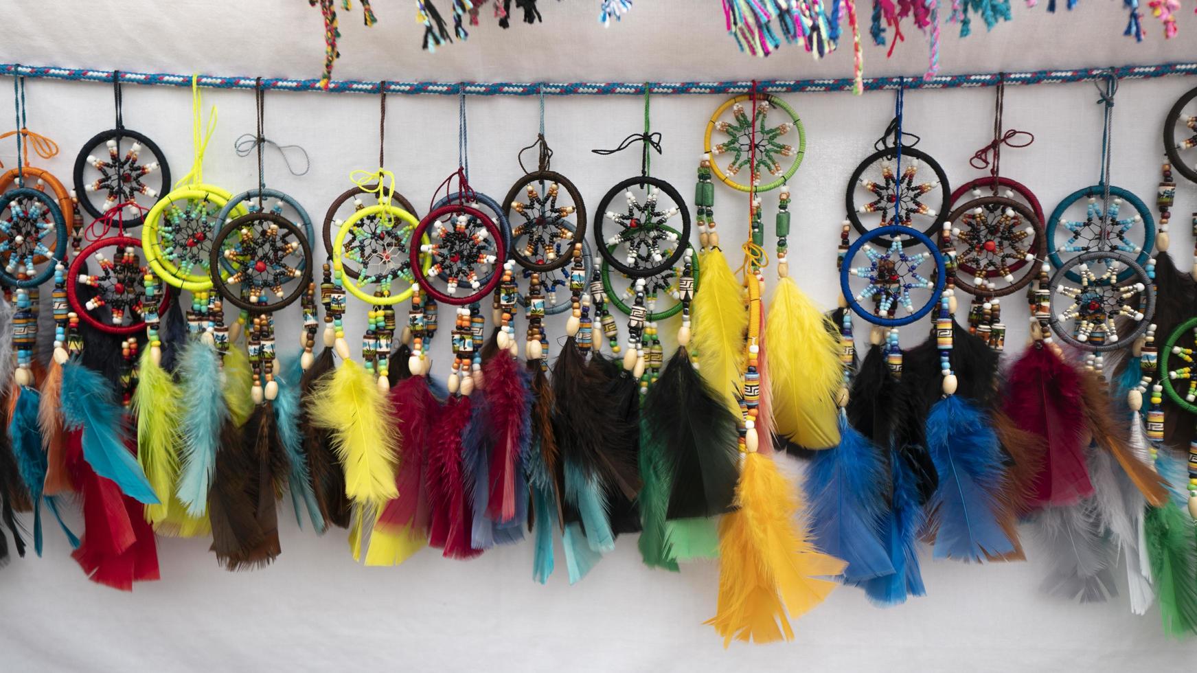 Quito, Ecuador, 2022 - Group of multicolored dreamcatchers with feathers made by hand by indigenous Ecuadorians for sale in an artisan market photo