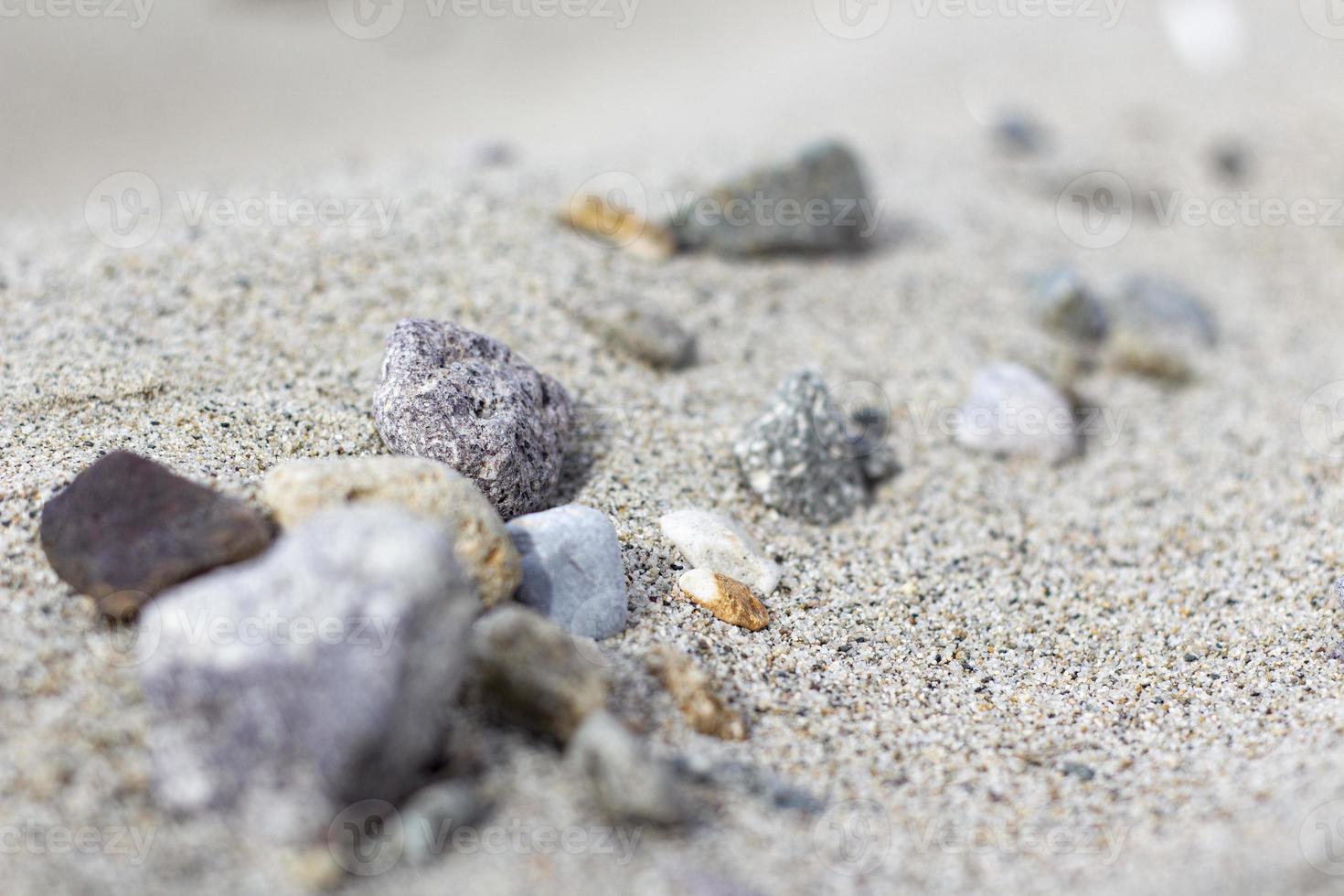 Sand mountain on the beach full of stones, blurry sea, and sand background. a pile of nice beach sand with and stones photo