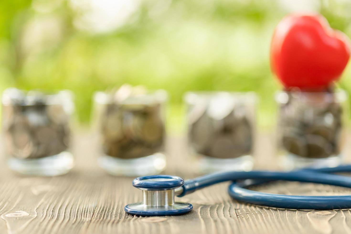 Blue stethoscope and jar of coin on wooden table. Money and financial checking concept photo