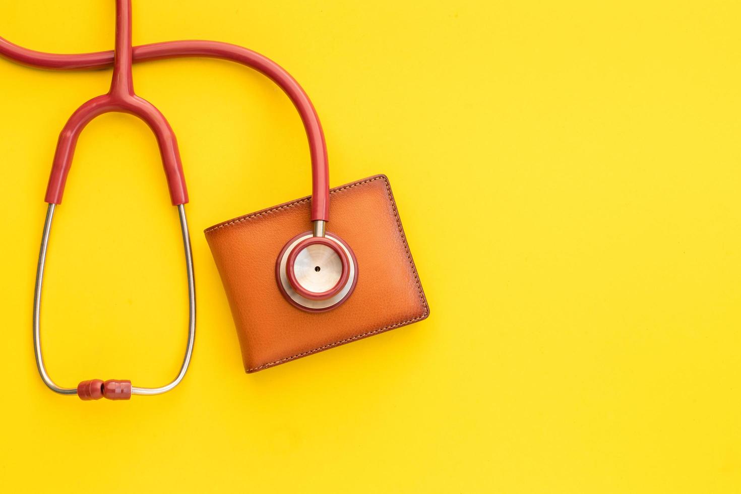 Doctor stethoscope and the new leather brown men wallet on yellow background. Budget for health check or money and financial concept photo