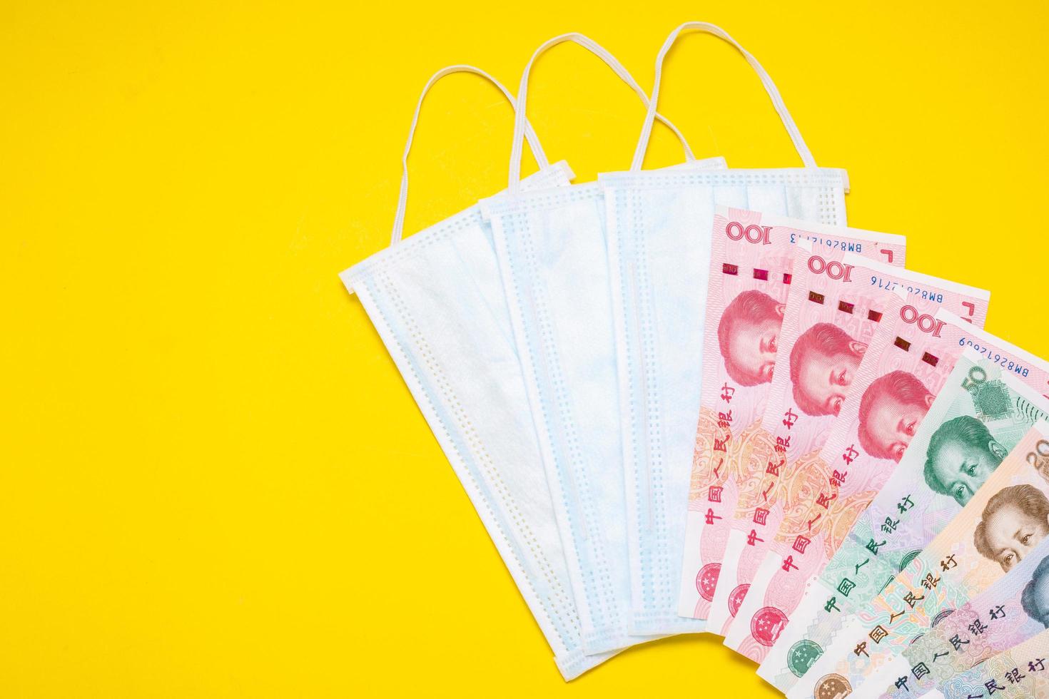 Chinese banknote  and new white mask on yellow. Mask is important but lack and very expensive in many country of Virus situation in 2020 photo