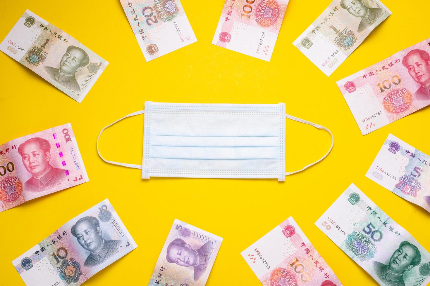 Chinese banknote  and new white mask on yellow. Mask is important but lack and very expensive in many country of Virus situation in 2020 photo