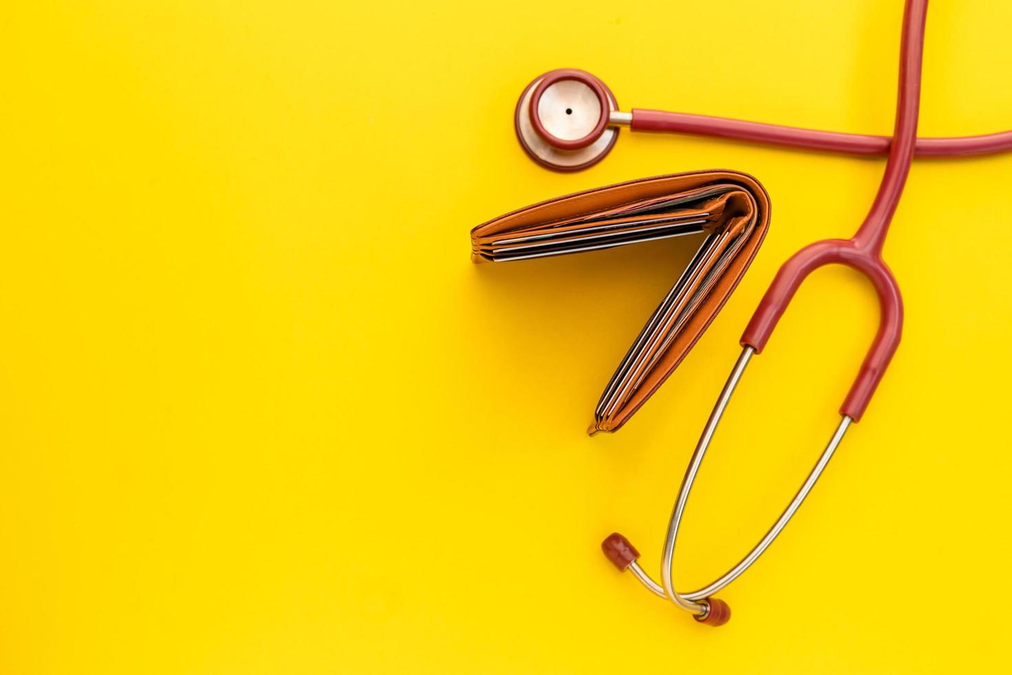 Doctor stethoscope and the new leather brown men wallet on yellow background. Budget for health check or money and financial concept photo