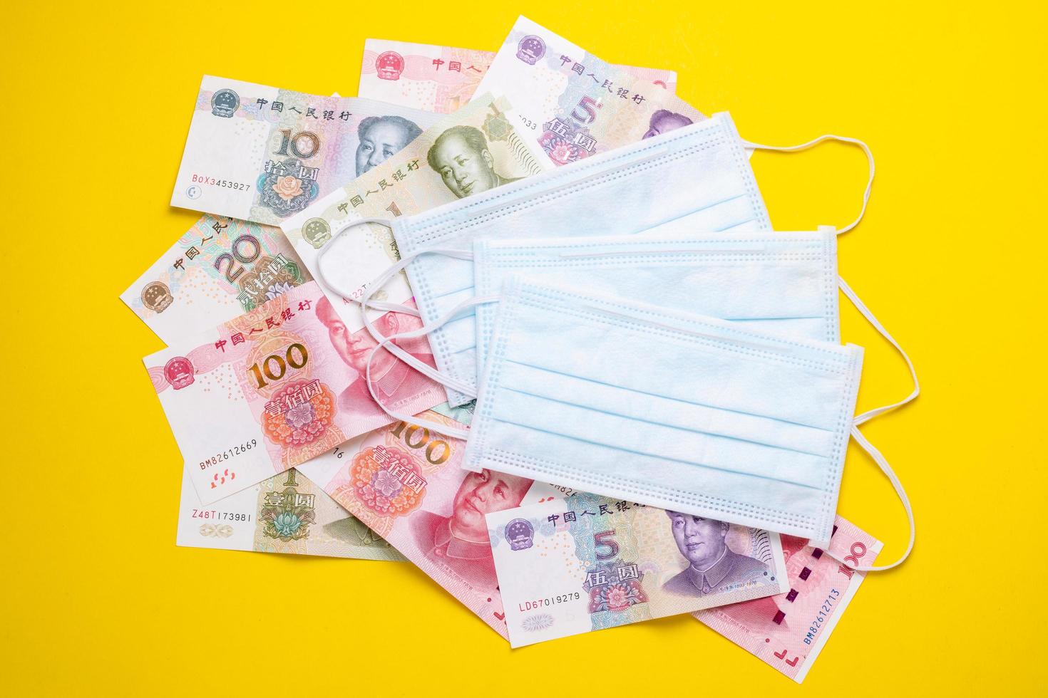 Chinese banknote  and new white mask on yellow. Mask is important but lack and very expensive in many country of Virus situation in 2020 photo