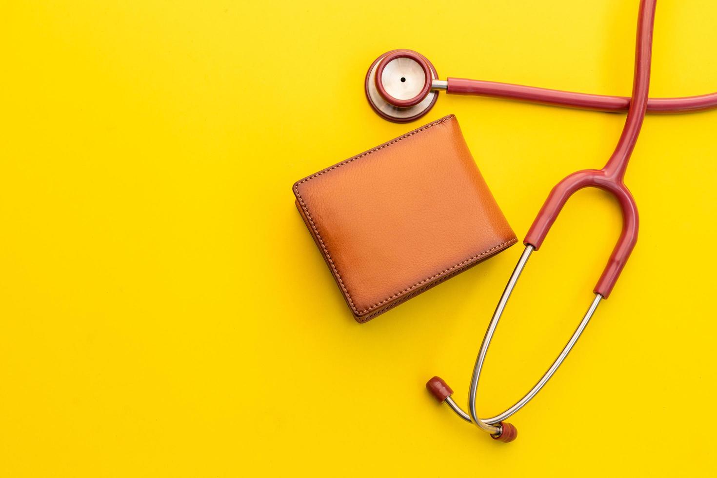 Doctor stethoscope and the new leather brown men wallet on yellow background. Budget for health check or money and financial concept photo