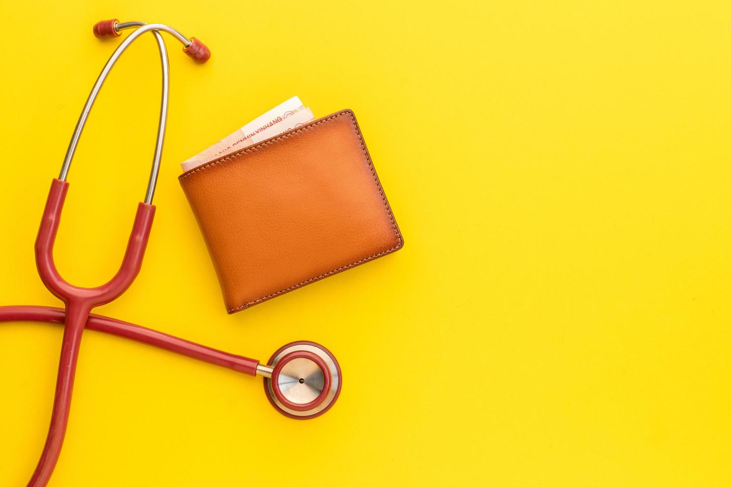 Doctor stethoscope and the new leather brown men wallet on yellow background. Budget for health check or money and financial concept photo