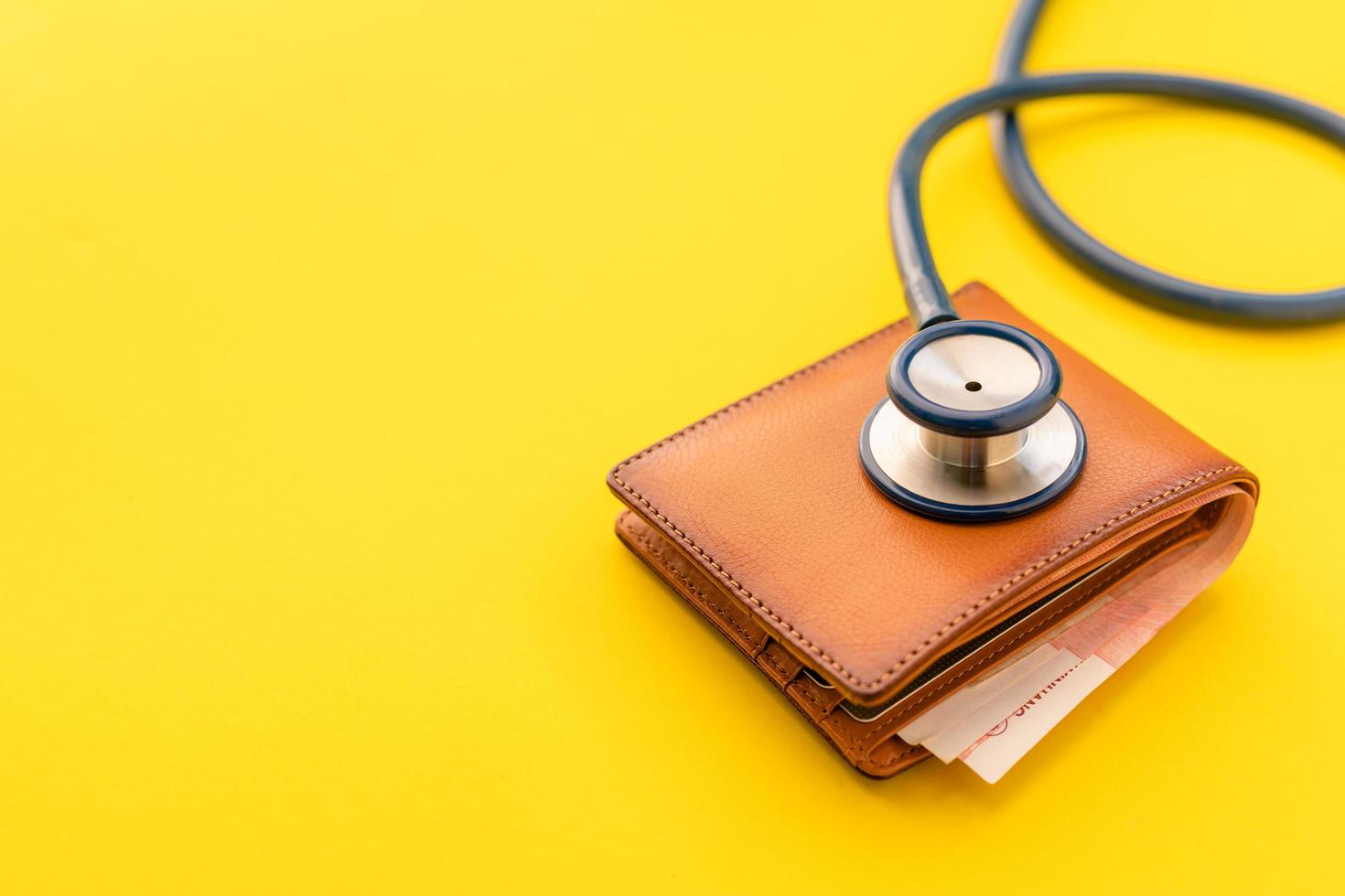 Doctor stethoscope and the new leather brown men wallet on yellow background. Budget for health check or money and financial concept photo