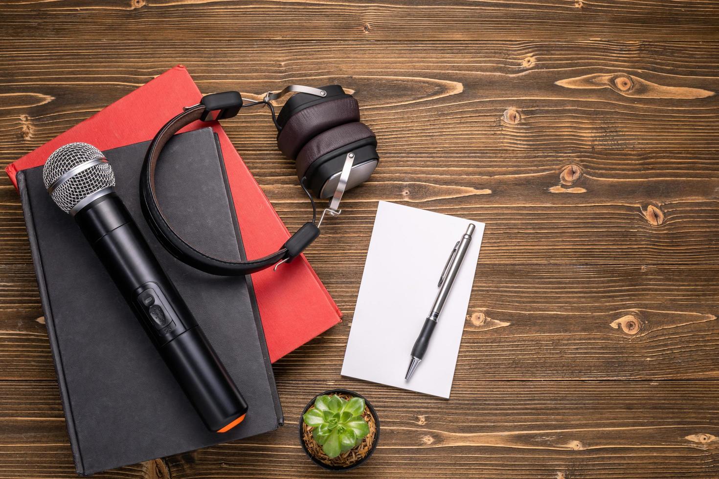 Microphone, headphone, book and paper note on brown wooden board. Learning about speaking concept photo