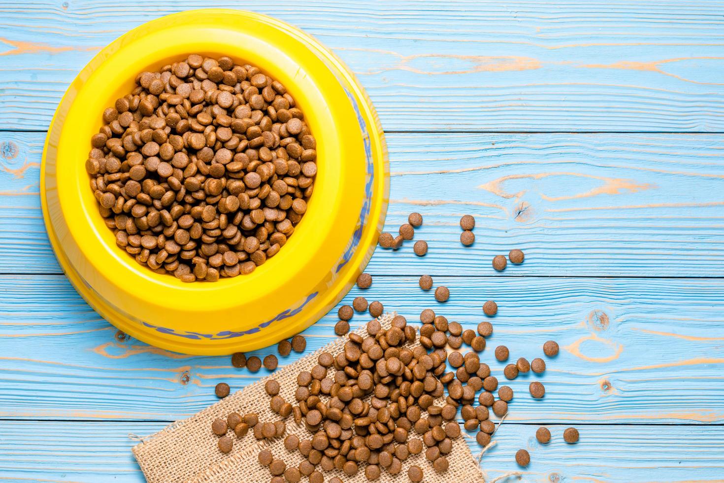 comida para perros en un recipiente de plástico amarillo sobre una tabla de madera foto