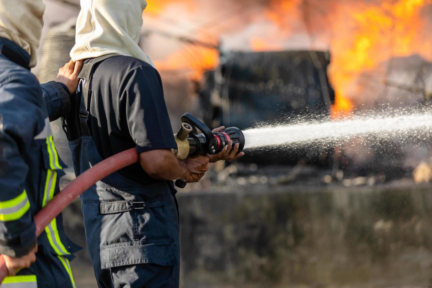 Firefighter spraying water from big water hose to prevent fire photo