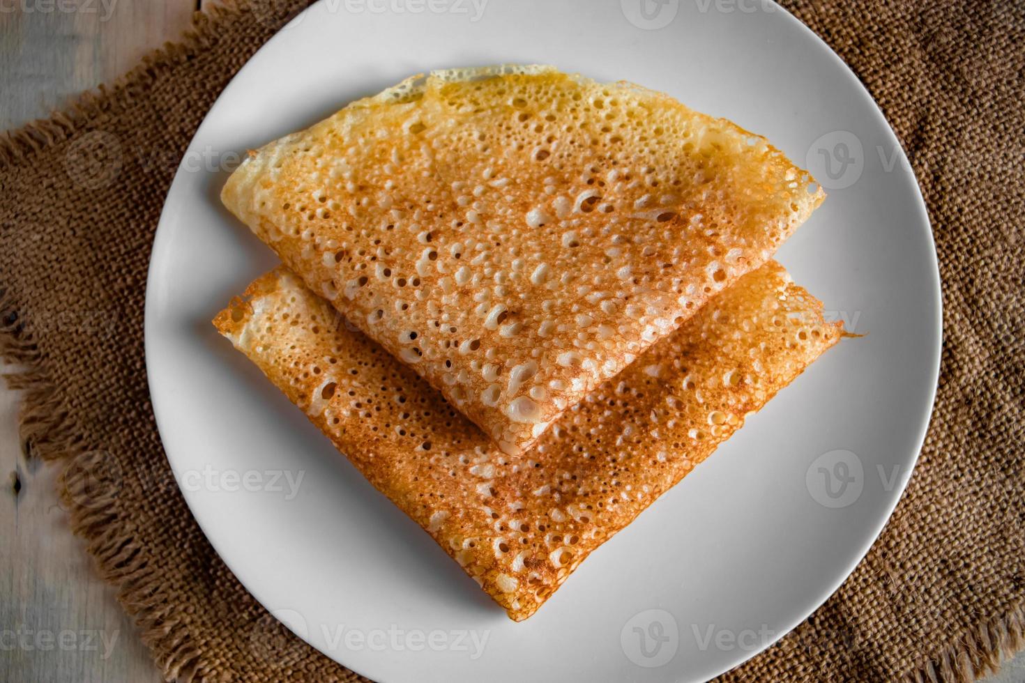 Pancakes on a white plate on a linen background. photo