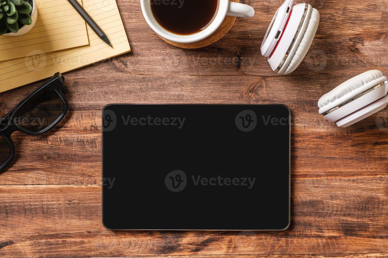 top view working desk with tablet ,keyboard headphone on wooden table background photo