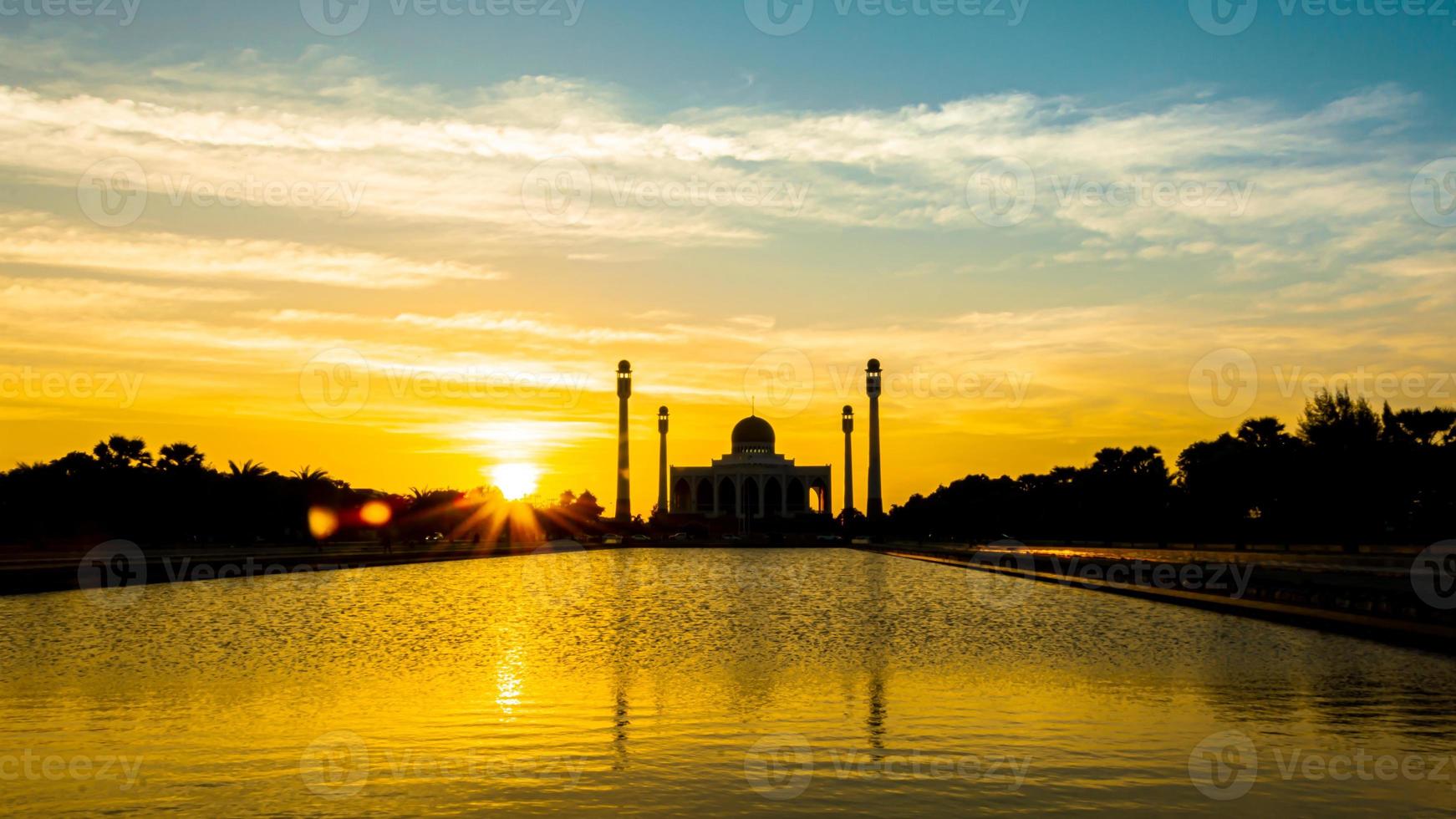 Songkhla Central Mosque in day to night with colorful skies at sunset and the lights of the mosque and reflections in the water in landmark landscape concept photo
