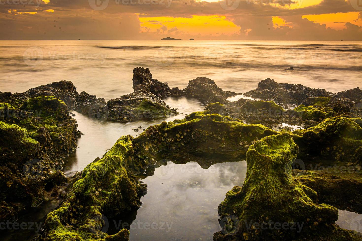 paisaje de puesta de sol en las rocas de la playa en primer plano foto