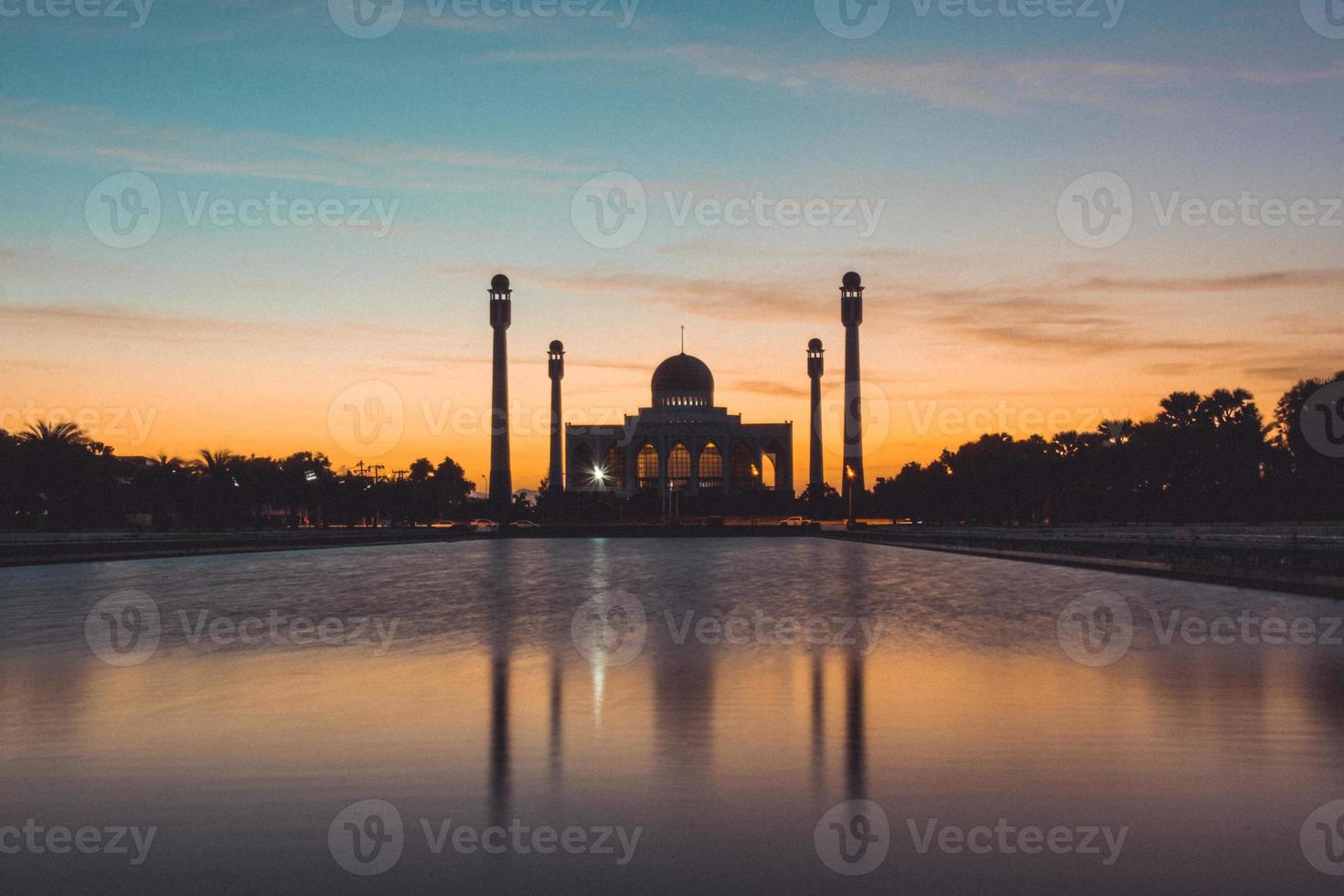 Songkhla Central Mosque in day to night with colorful skies at sunset and the lights of the mosque and reflections in the water in landmark landscape concept photo