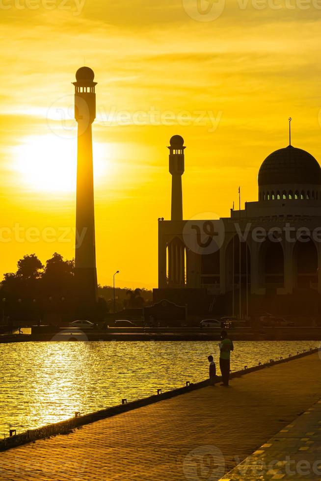 Songkhla Central Mosque in day to night with colorful skies at sunset and the lights of the mosque and reflections in the water in landmark landscape concept photo