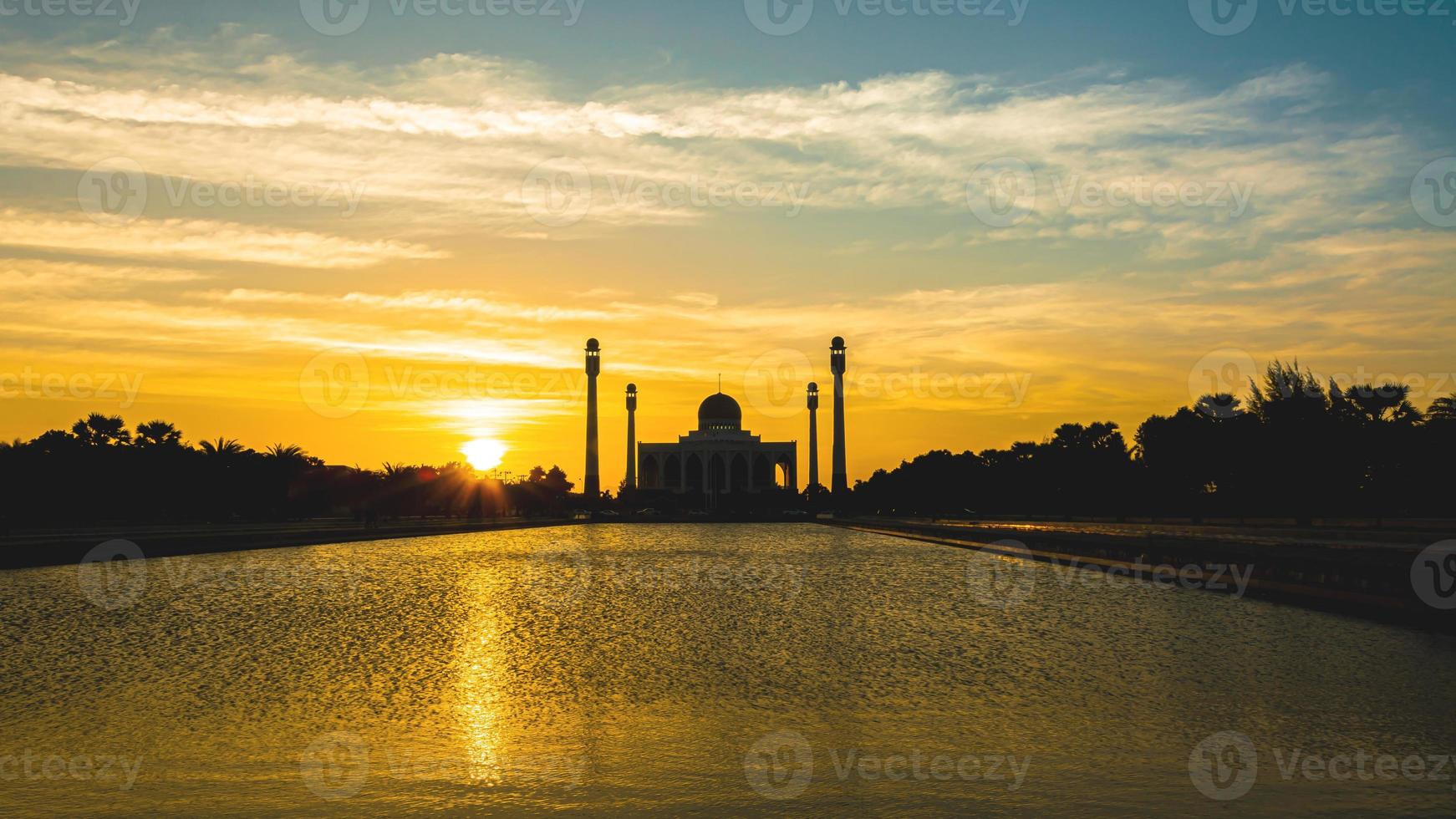 Songkhla Central Mosque in day to night with colorful skies at sunset and the lights of the mosque and reflections in the water in landmark landscape concept photo