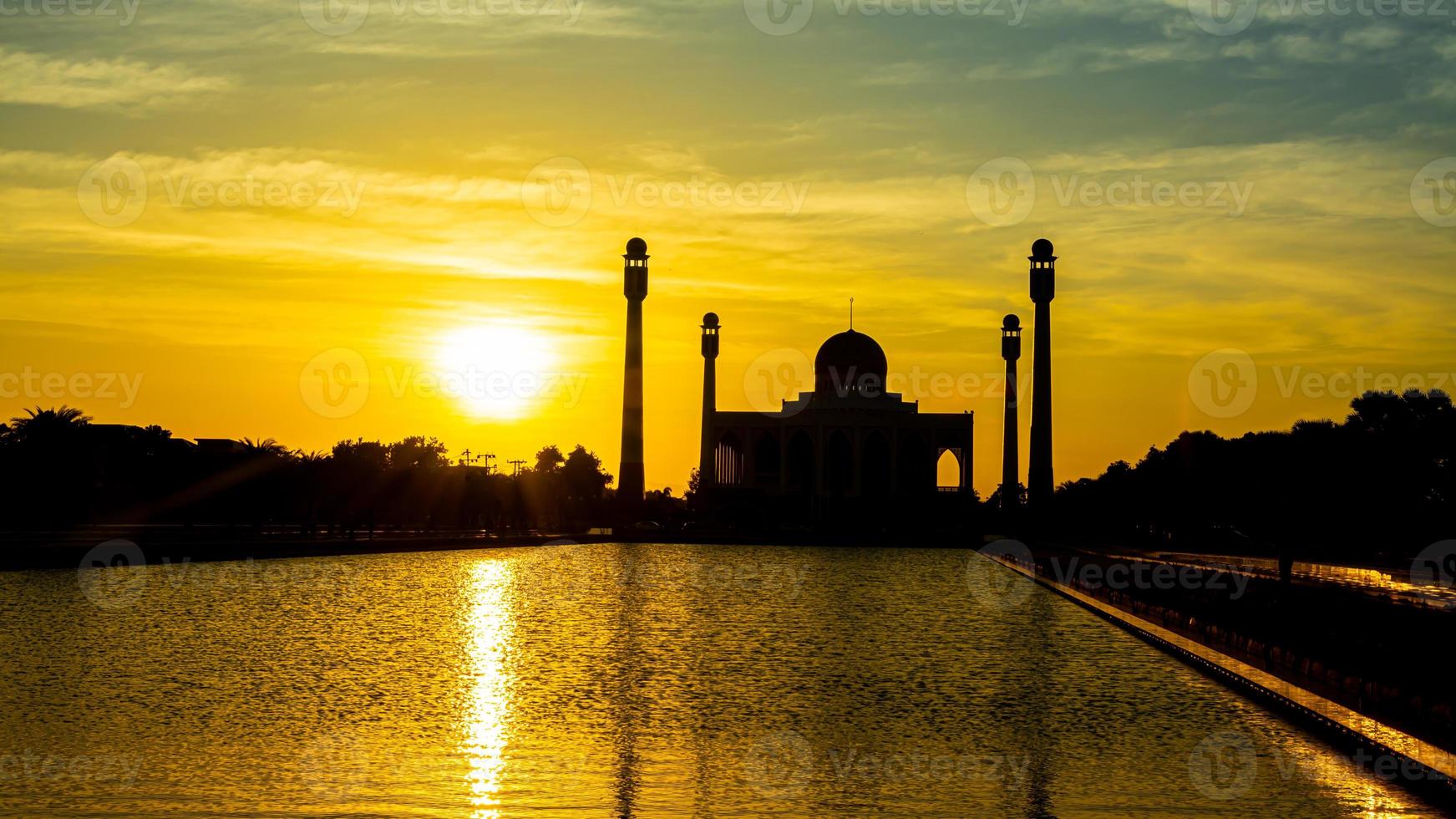 Songkhla Central Mosque in day to night with colorful skies at sunset and the lights of the mosque and reflections in the water in landmark landscape concept photo