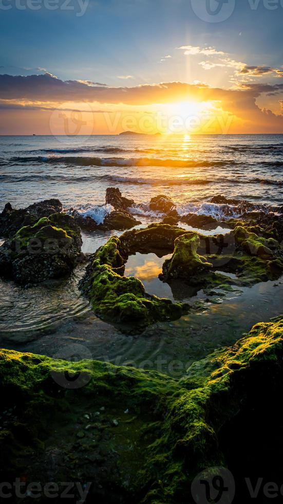 sunset landscape on the beach rocks in foreground photo