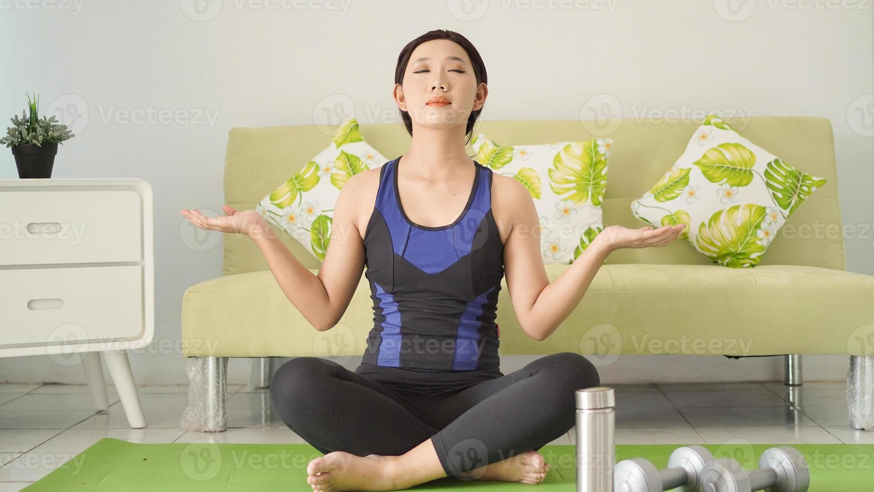 Asian woman practicing yoga at home with full concentration photo