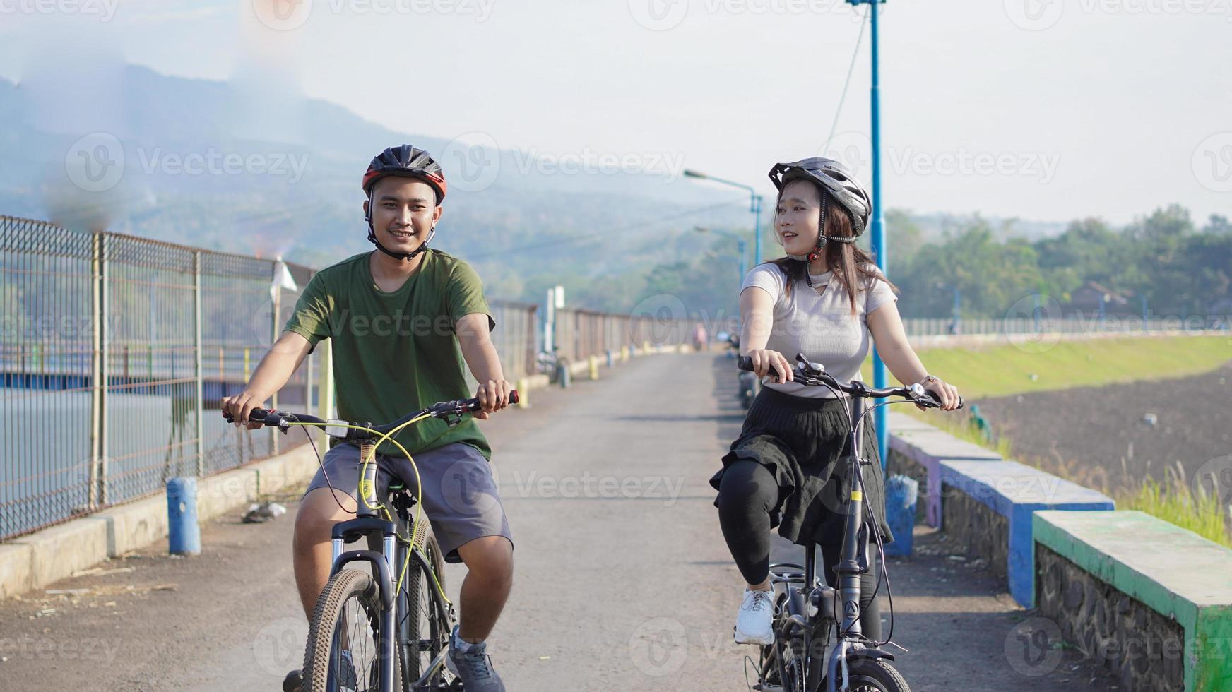 joven pareja asiática andar en bicicleta juntos por la mañana foto