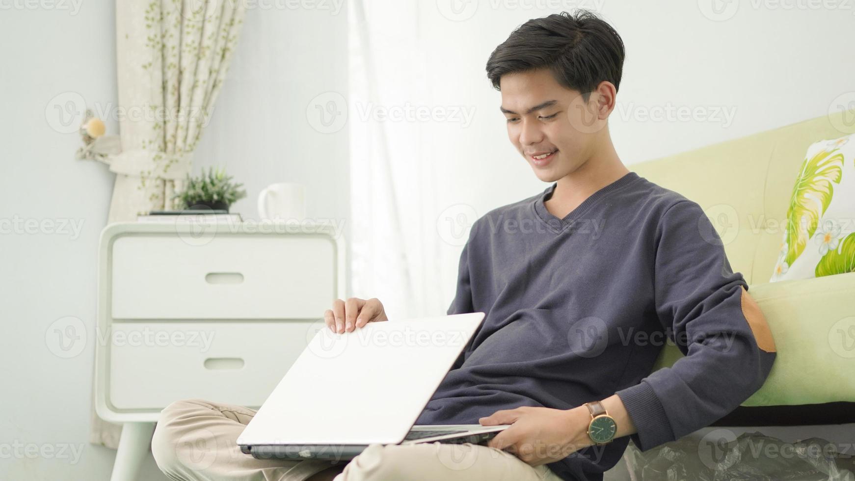 handsome asian man turning off his laptop after working at home photo