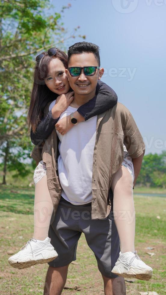 feliz pareja joven sosteniendo a su pareja en el parque en primavera foto