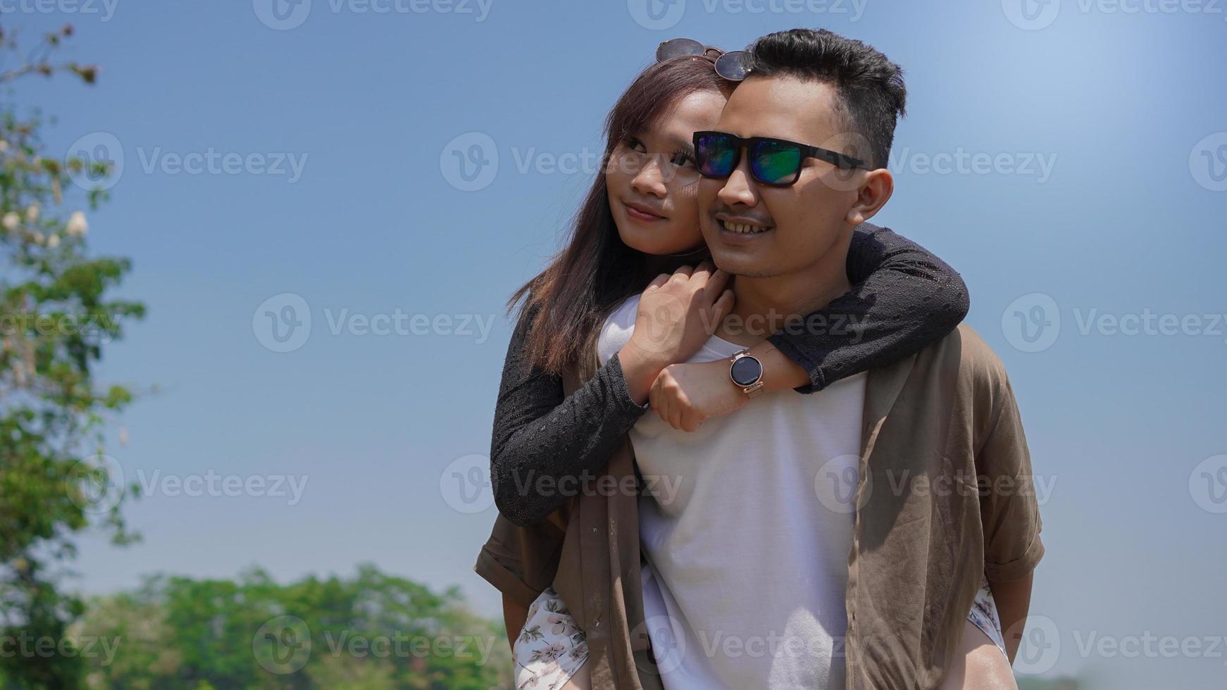 feliz pareja joven sosteniendo a su pareja en el lago en primavera foto