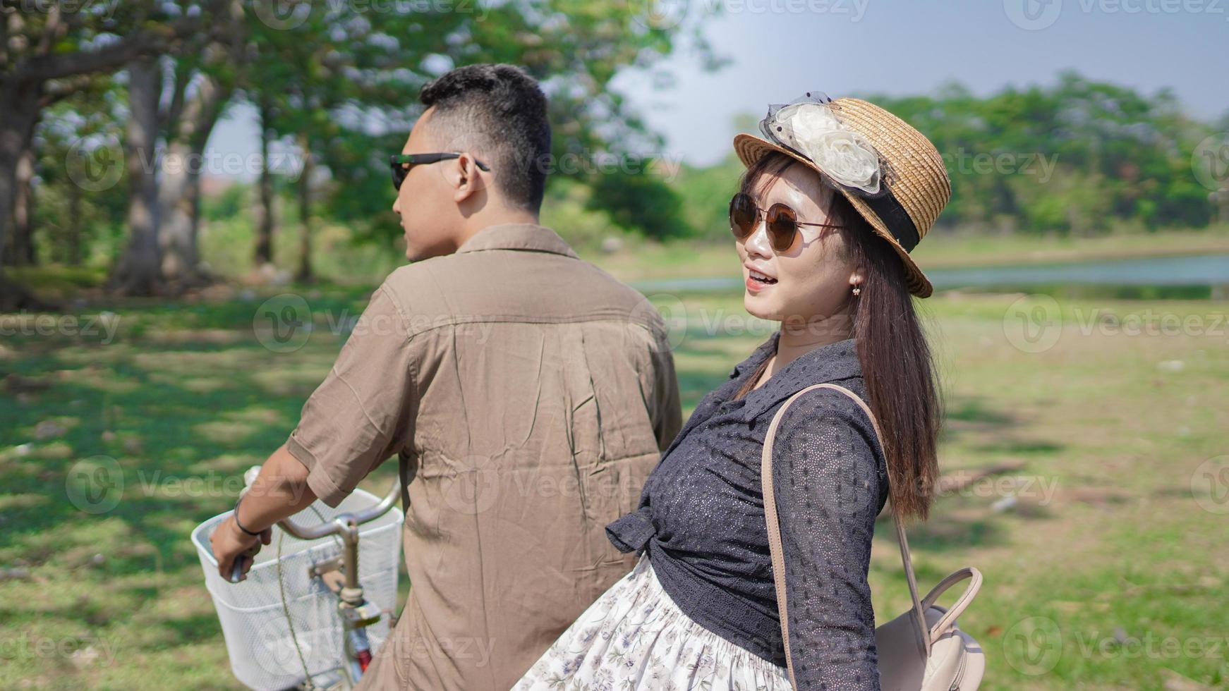 feliz pareja joven en bicicleta en el parque en verano foto